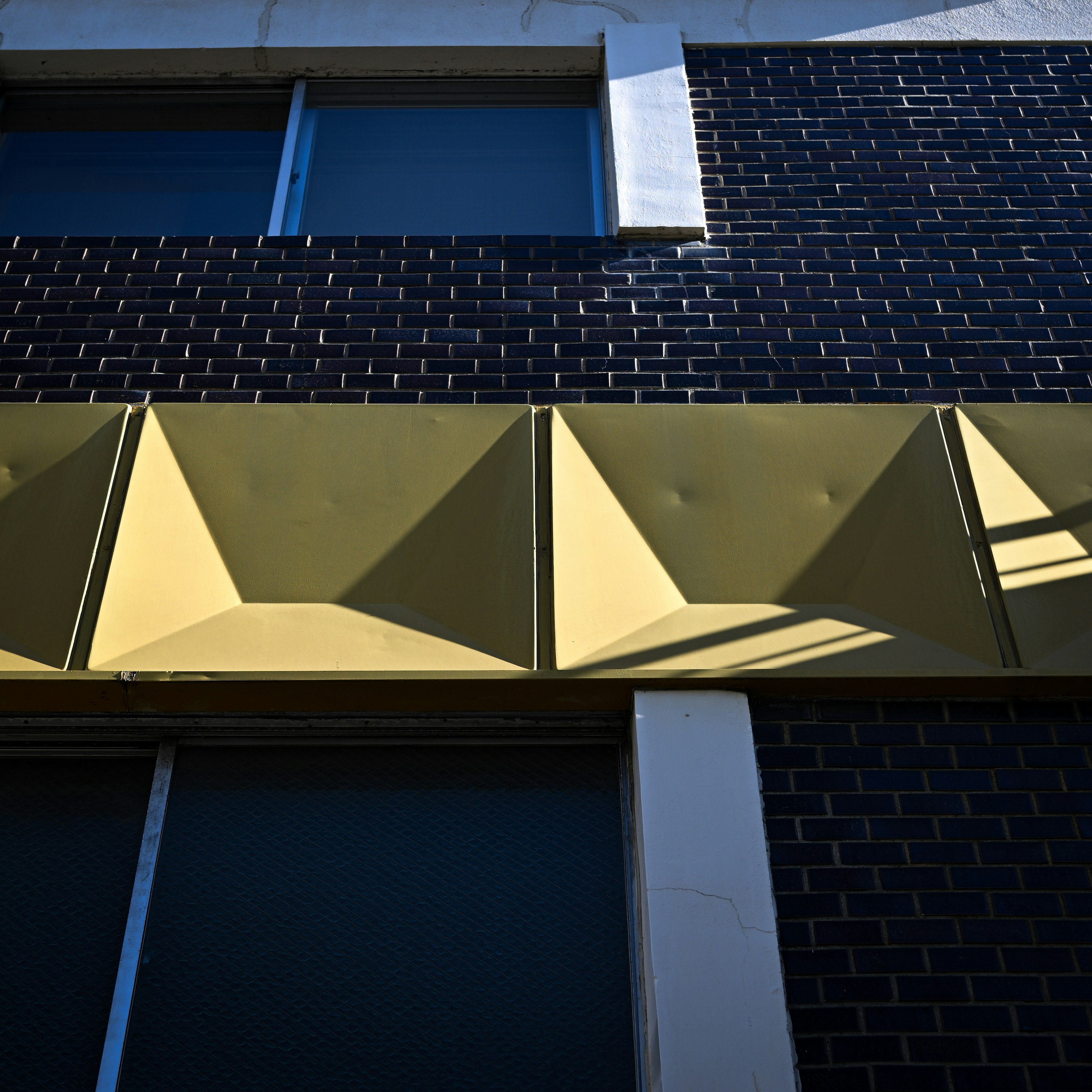 View of a gold decorative panel mounted on a black brick wall