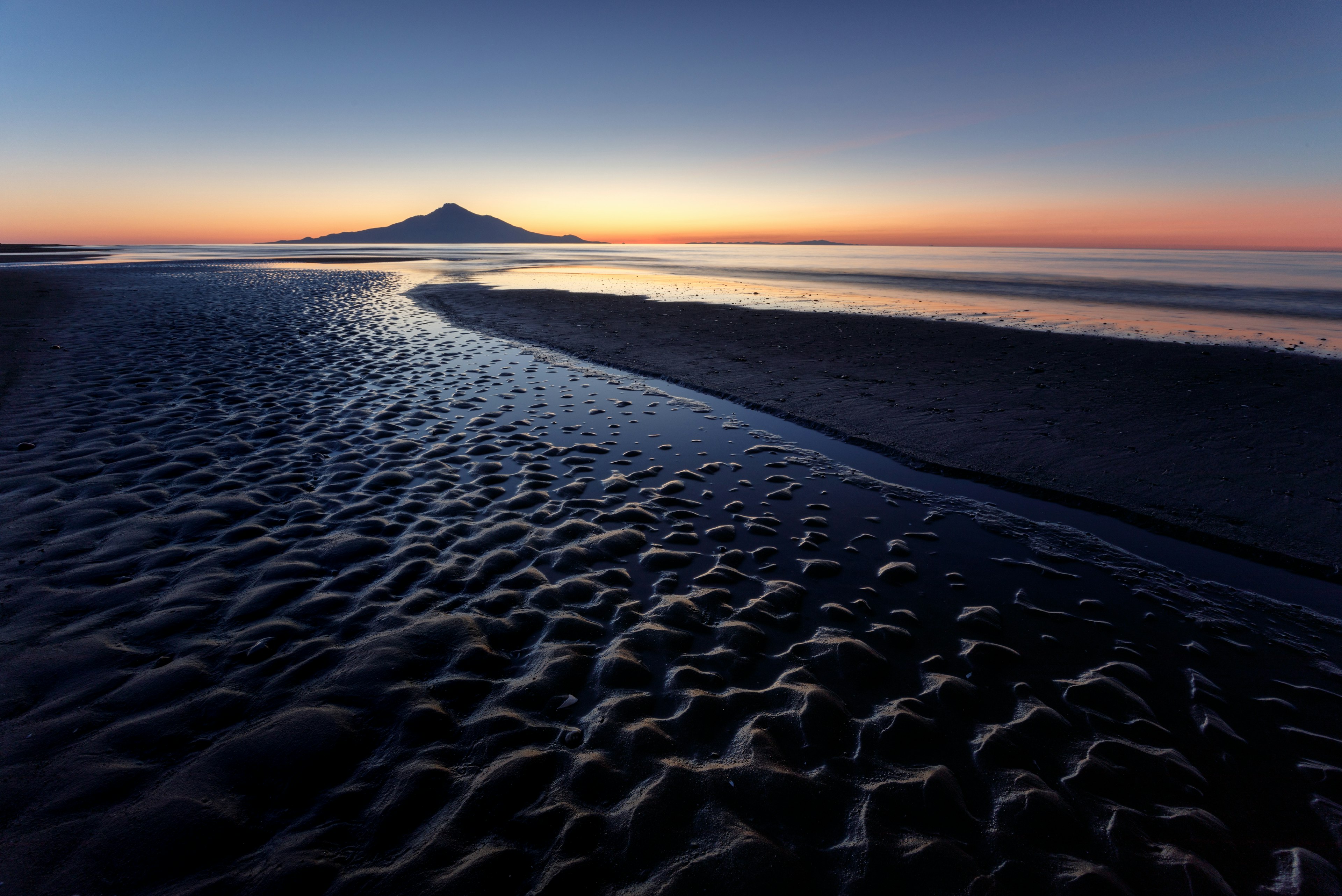 夕暮れの海岸線と波の形が特徴的な画像