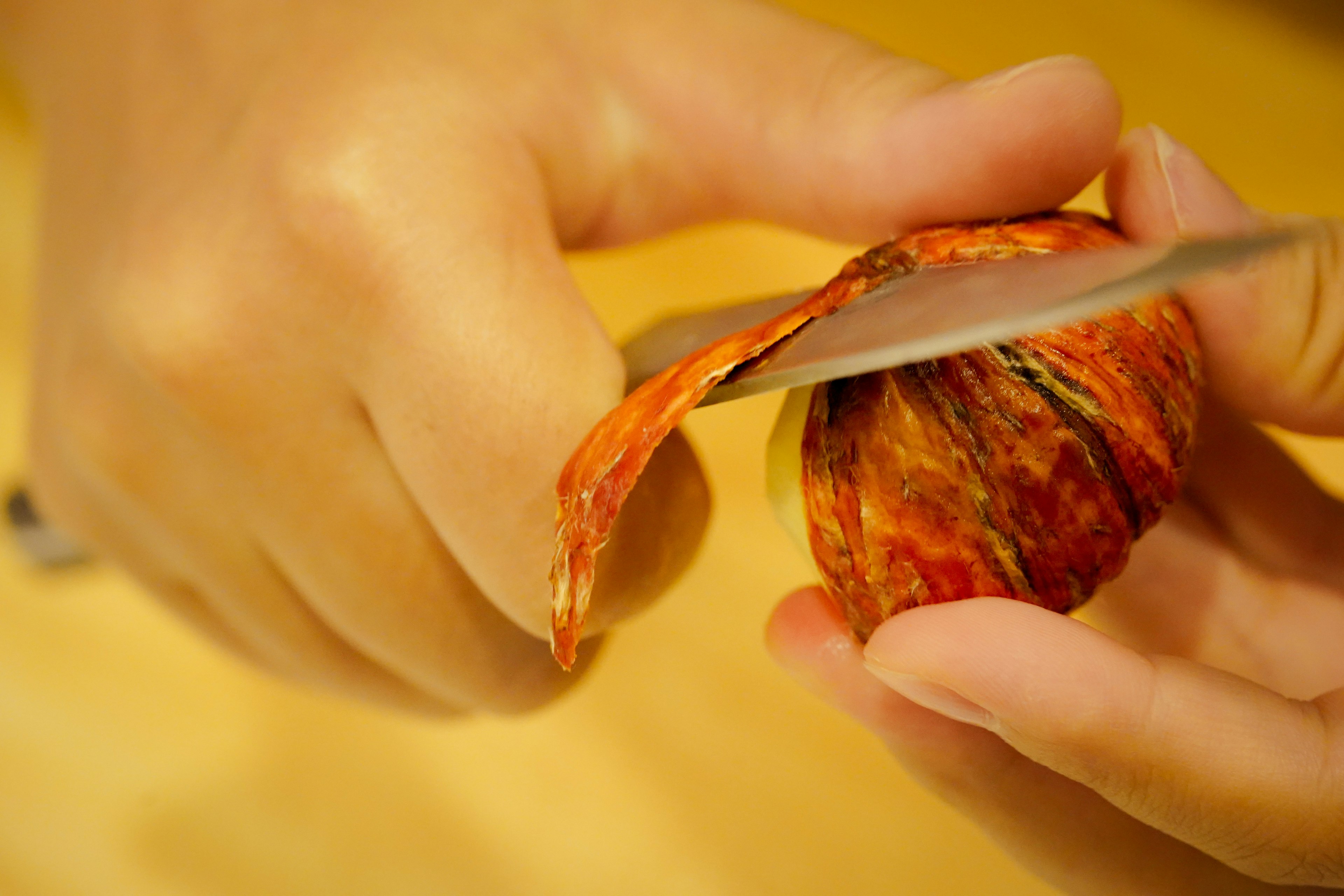 A person peeling a spice with a knife