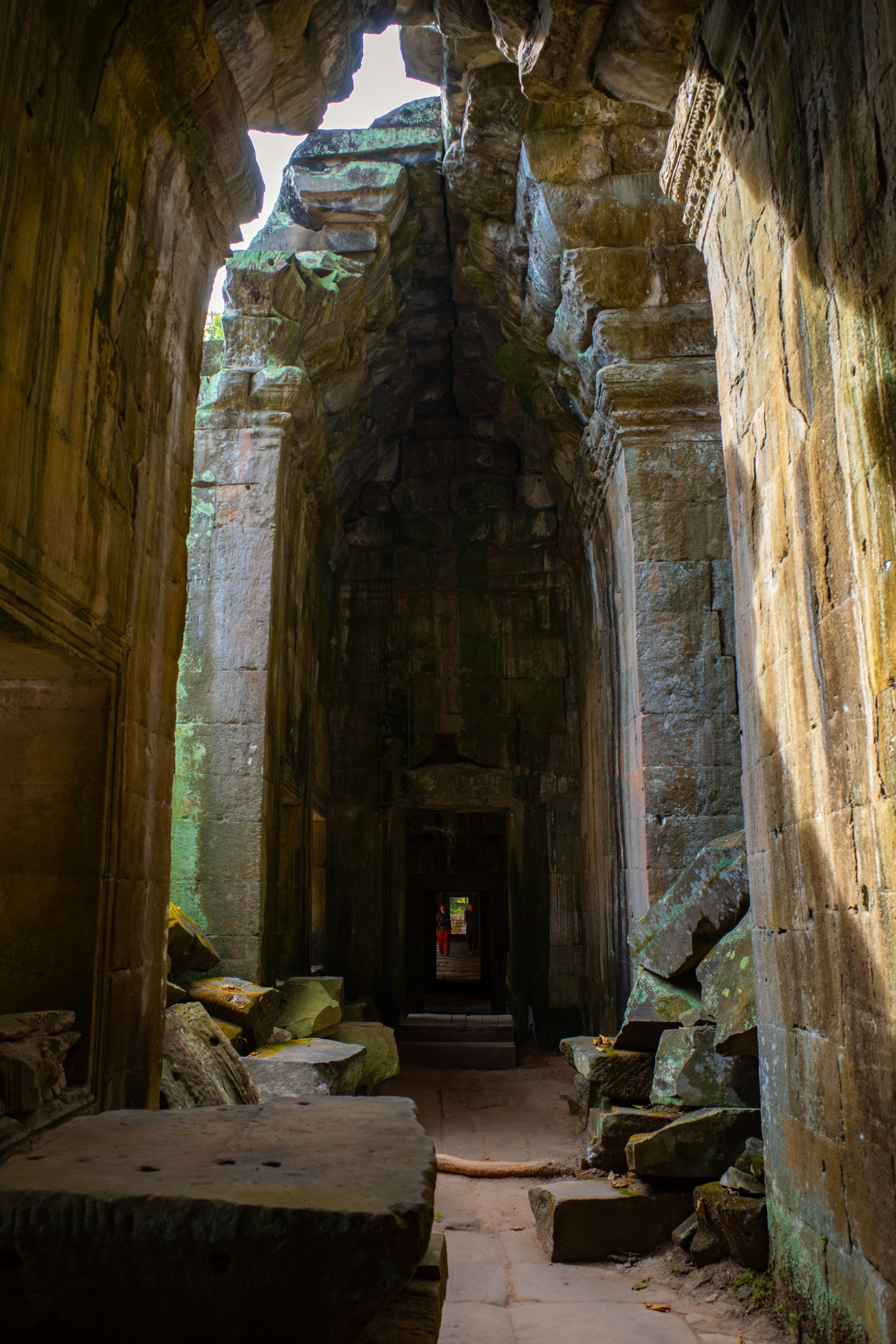 Passage étroit dans un ancien temple avec des pierres recouvertes de mousse le long des murs