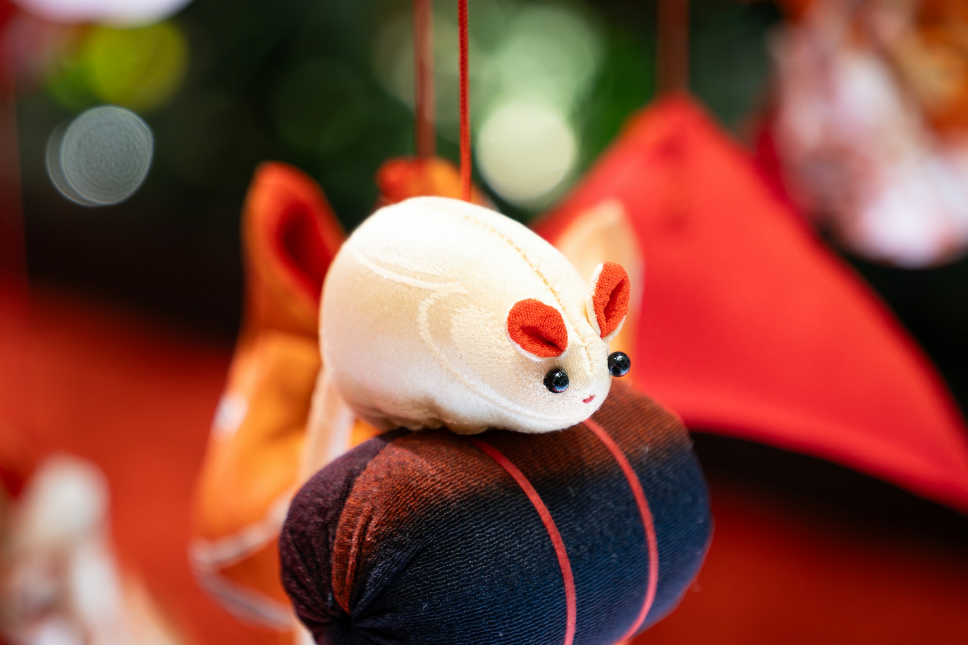 A small white mouse ornament sitting on colorful fabric balls