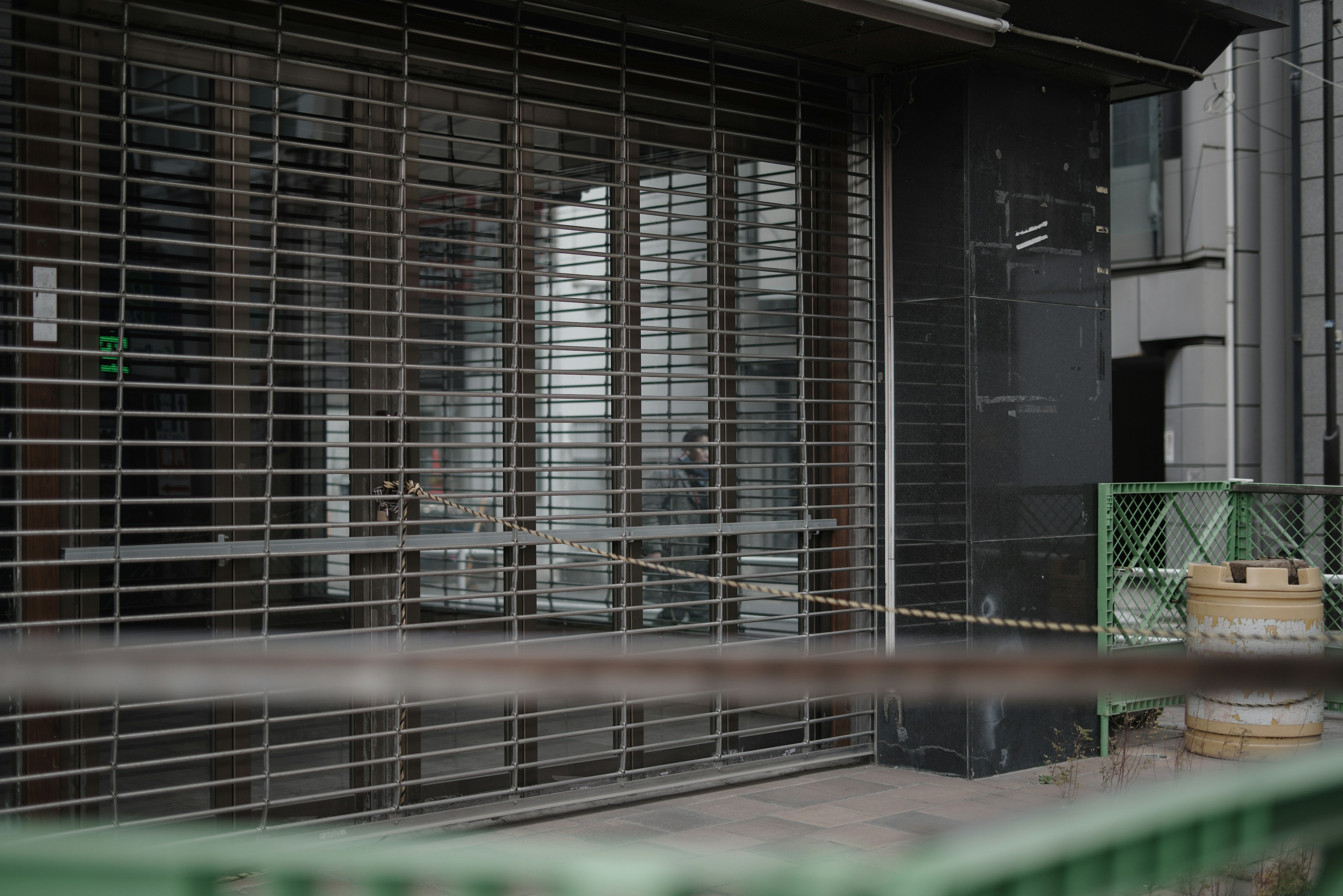 Exterior of a storefront with closed shutters and adjacent buildings