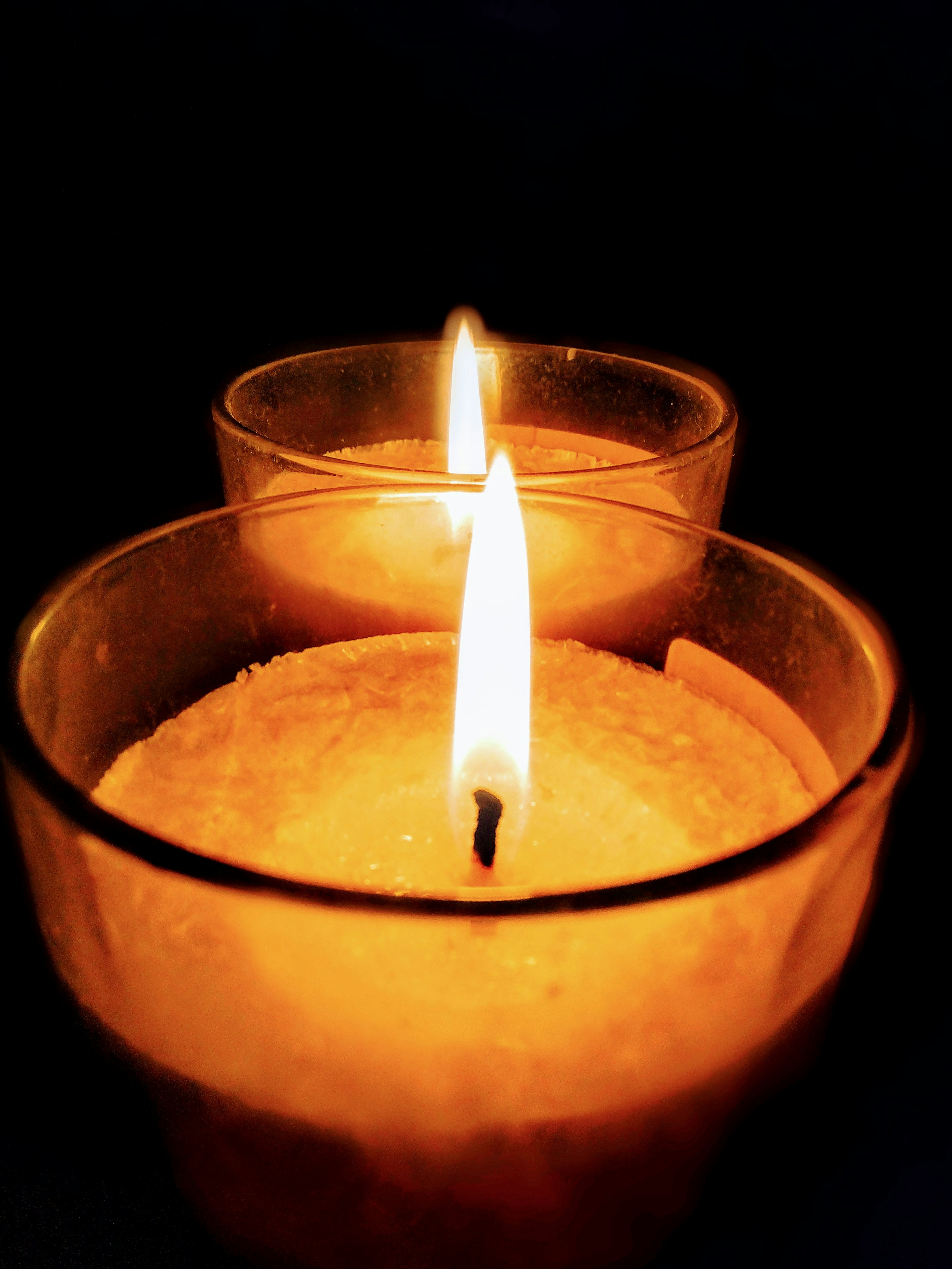 Two candles with flickering flames against a dark background