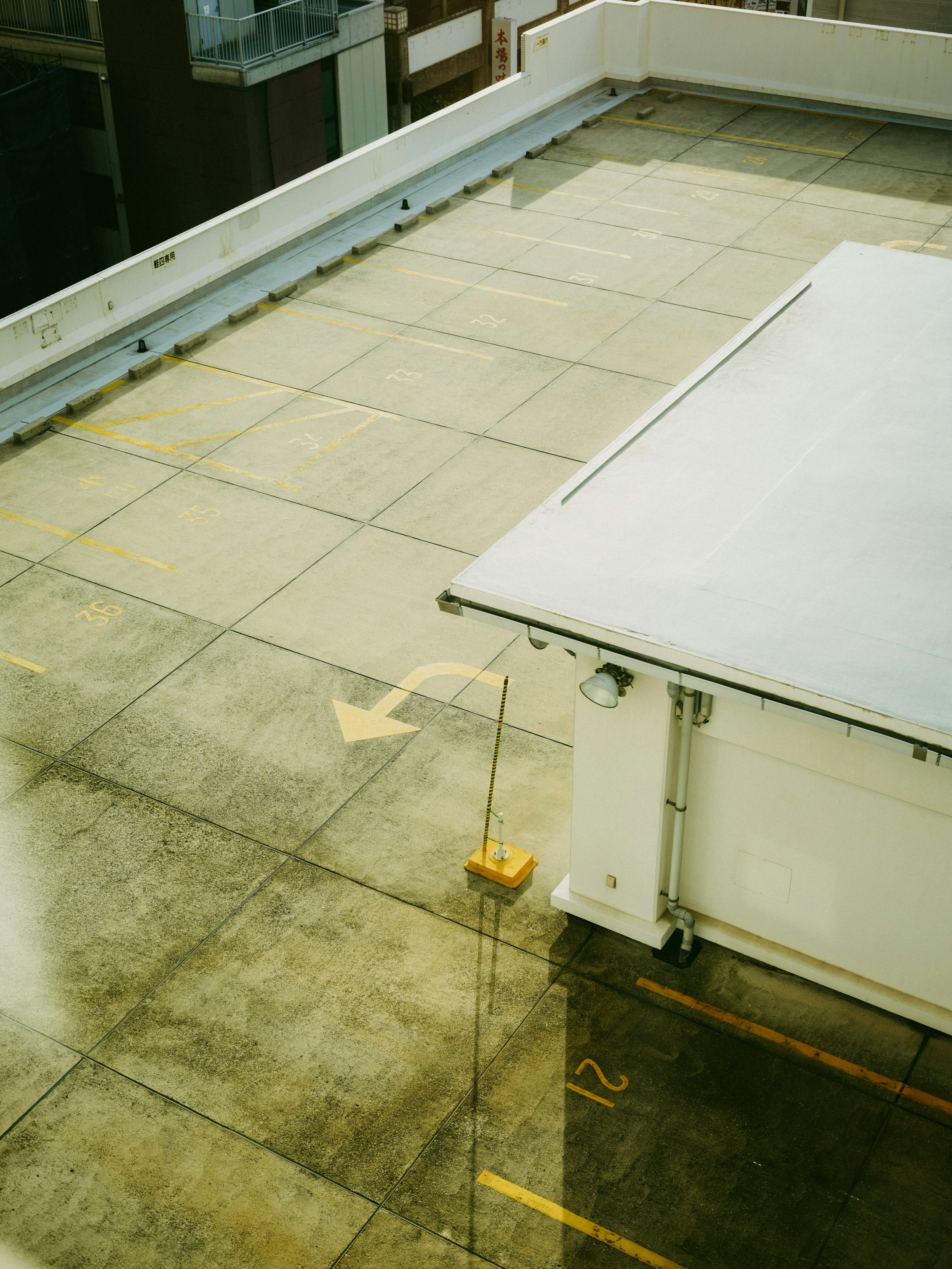 View of a rooftop parking area with concrete floor and yellow arrow markings