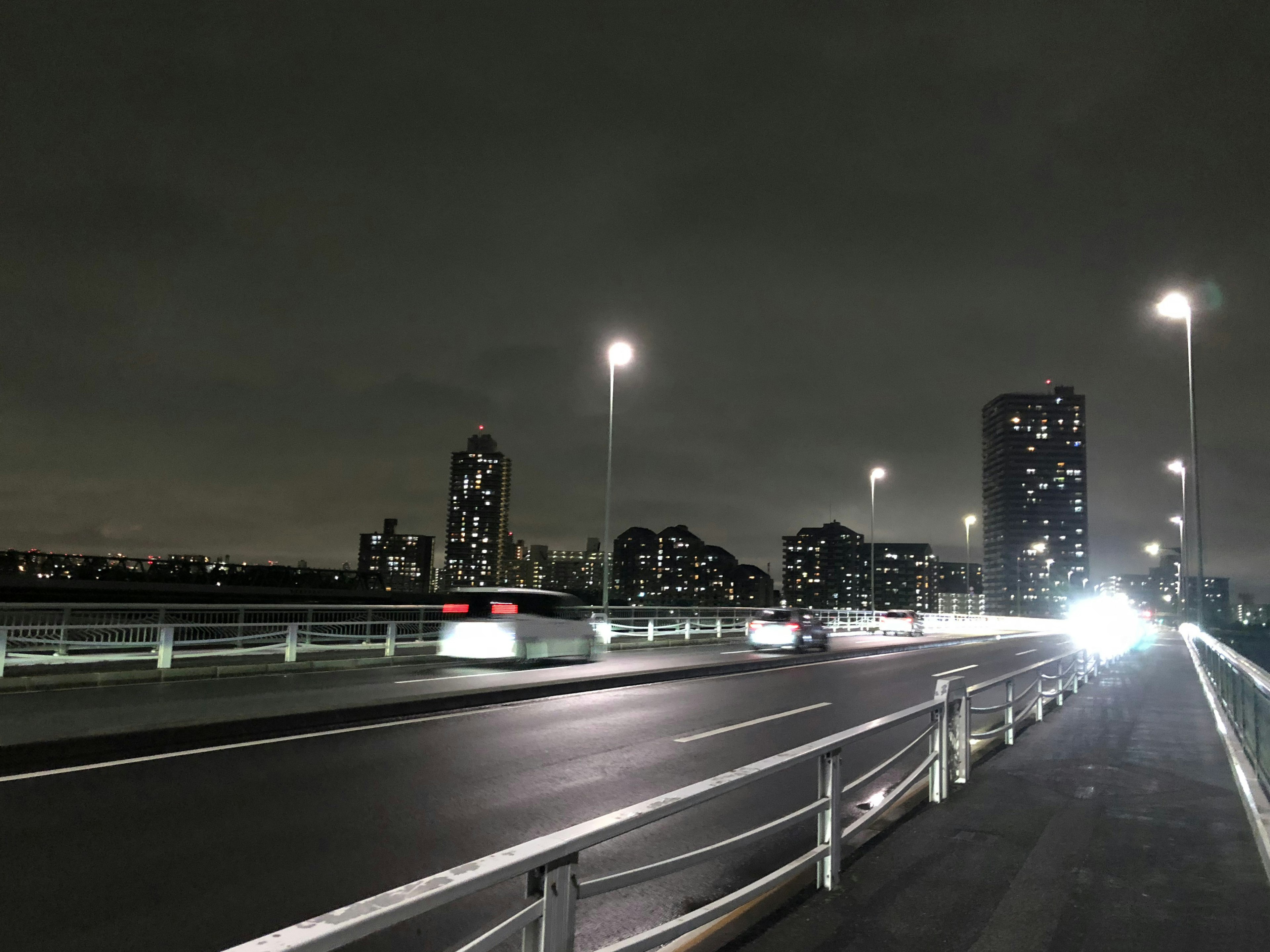 Nighttime cityscape featuring bright streetlights and a bridge