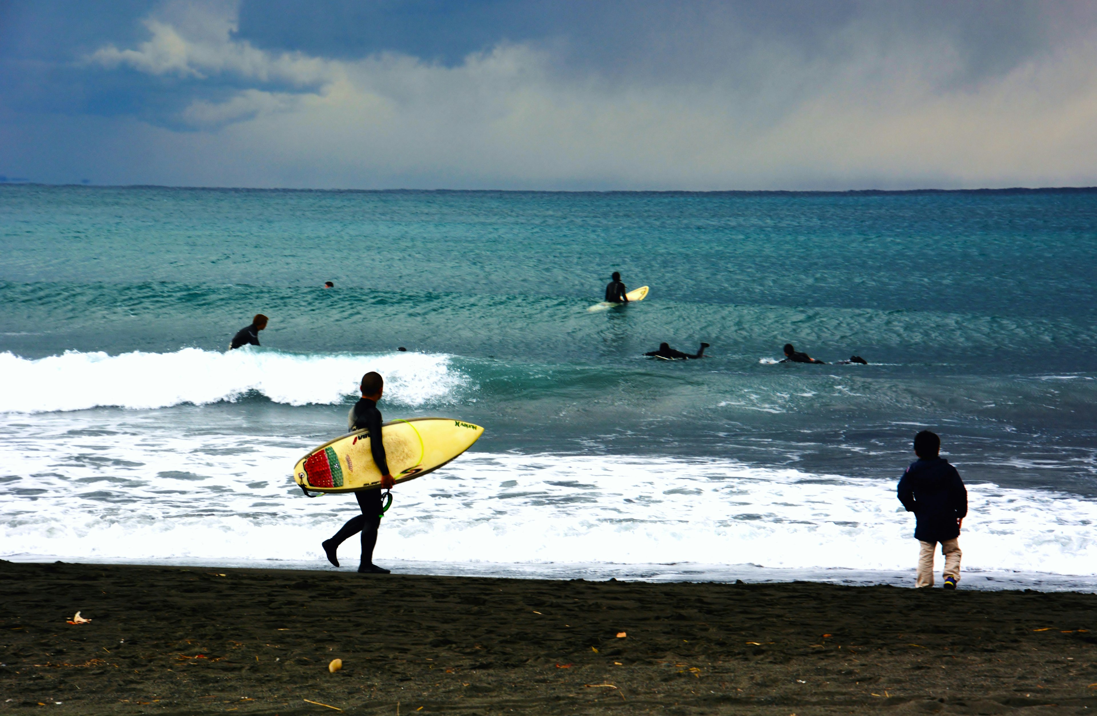 Gambar yang menunjukkan peselancar dan pemandangan pantai