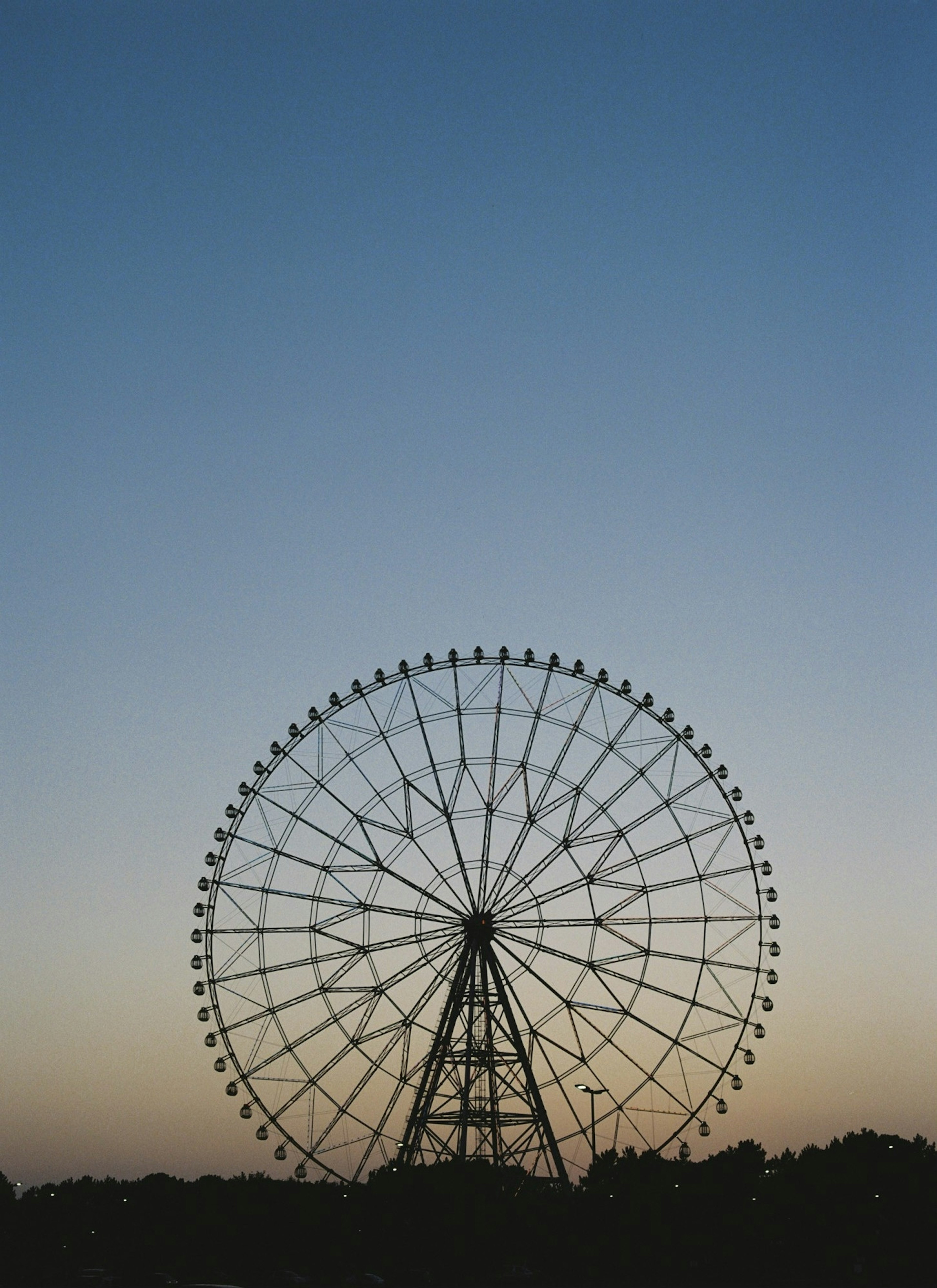 Silhouette of a ferris wheel against a twilight sky