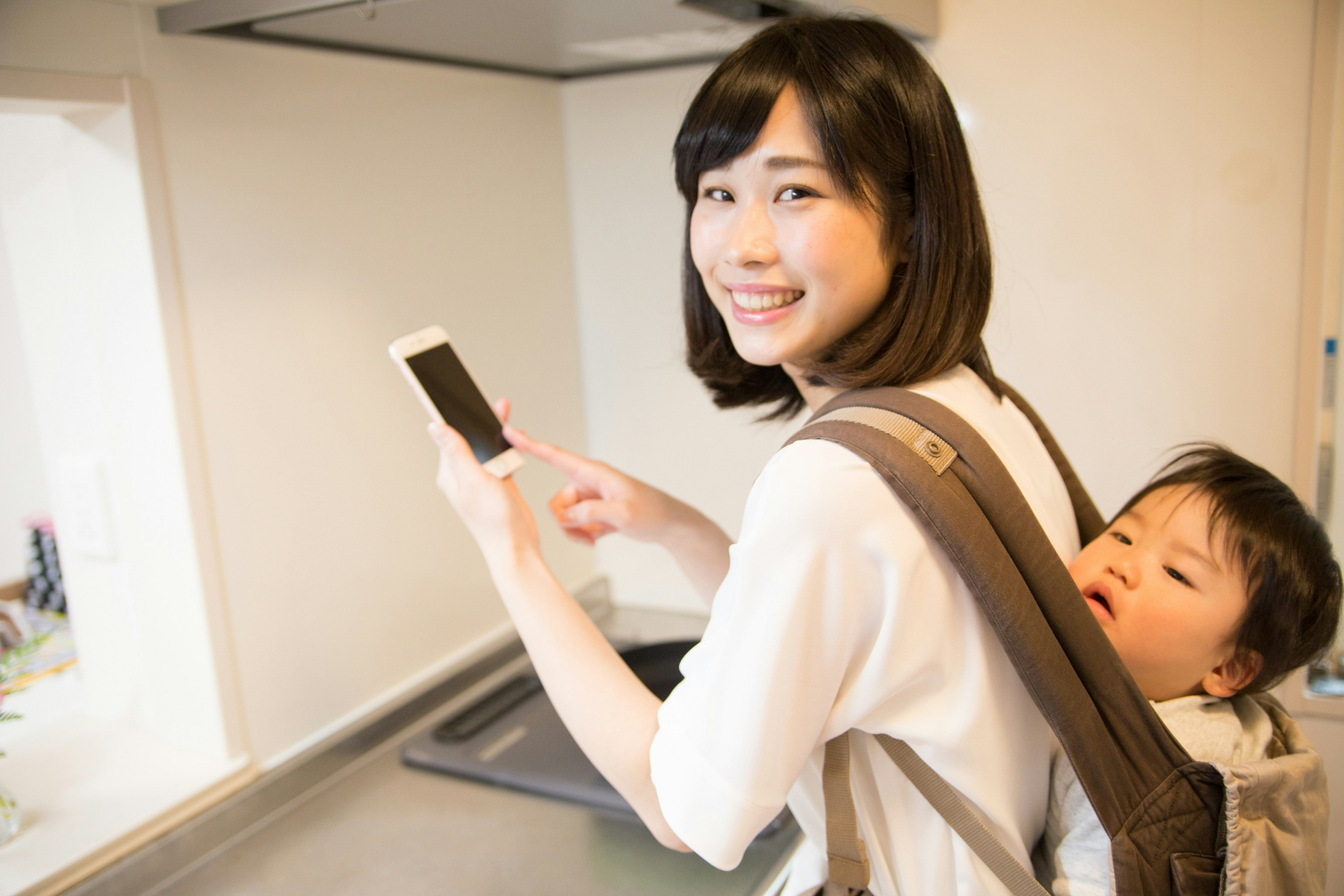 Mother using smartphone while carrying child on her back