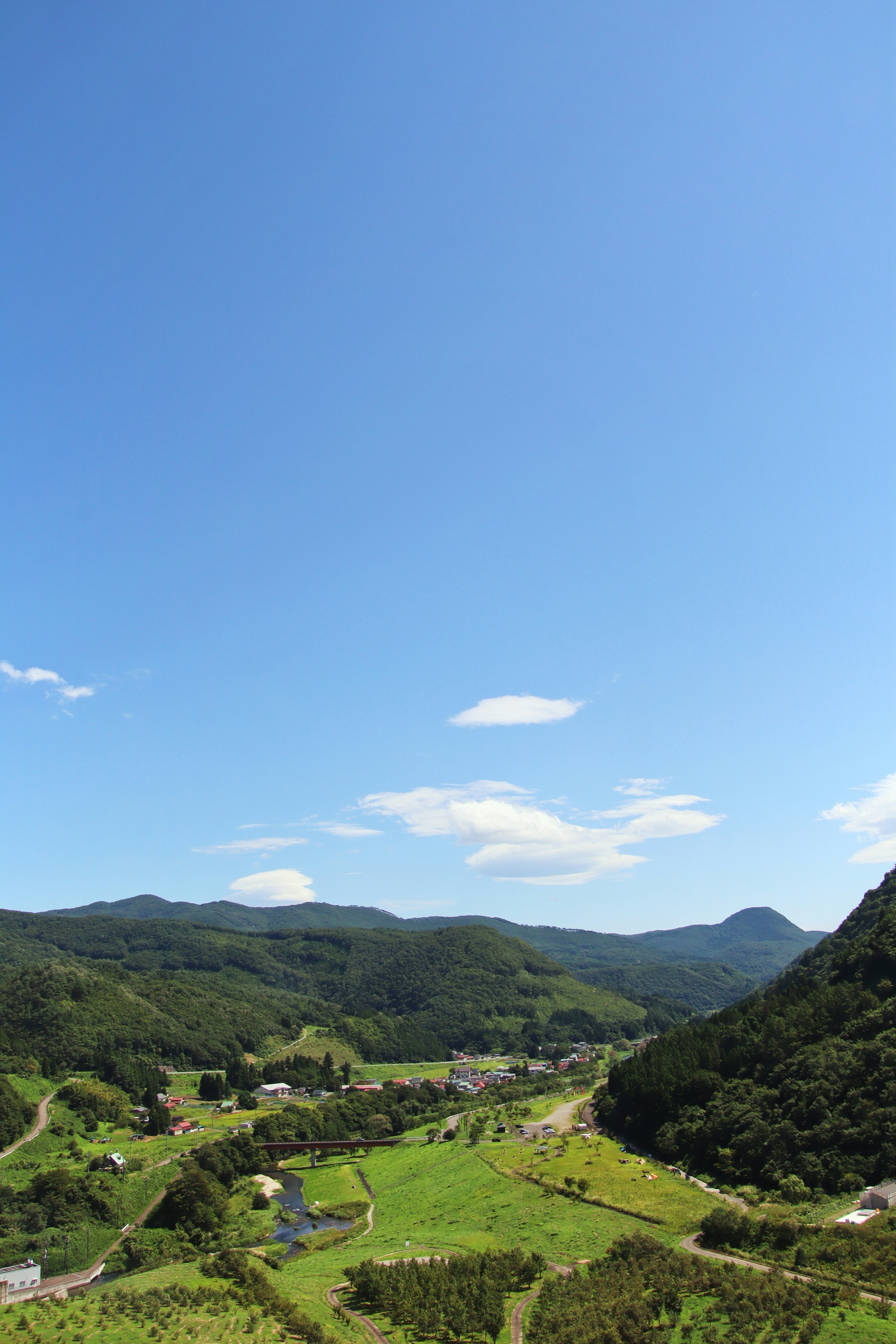 清澈蓝天下的绿色山丘和农田风景