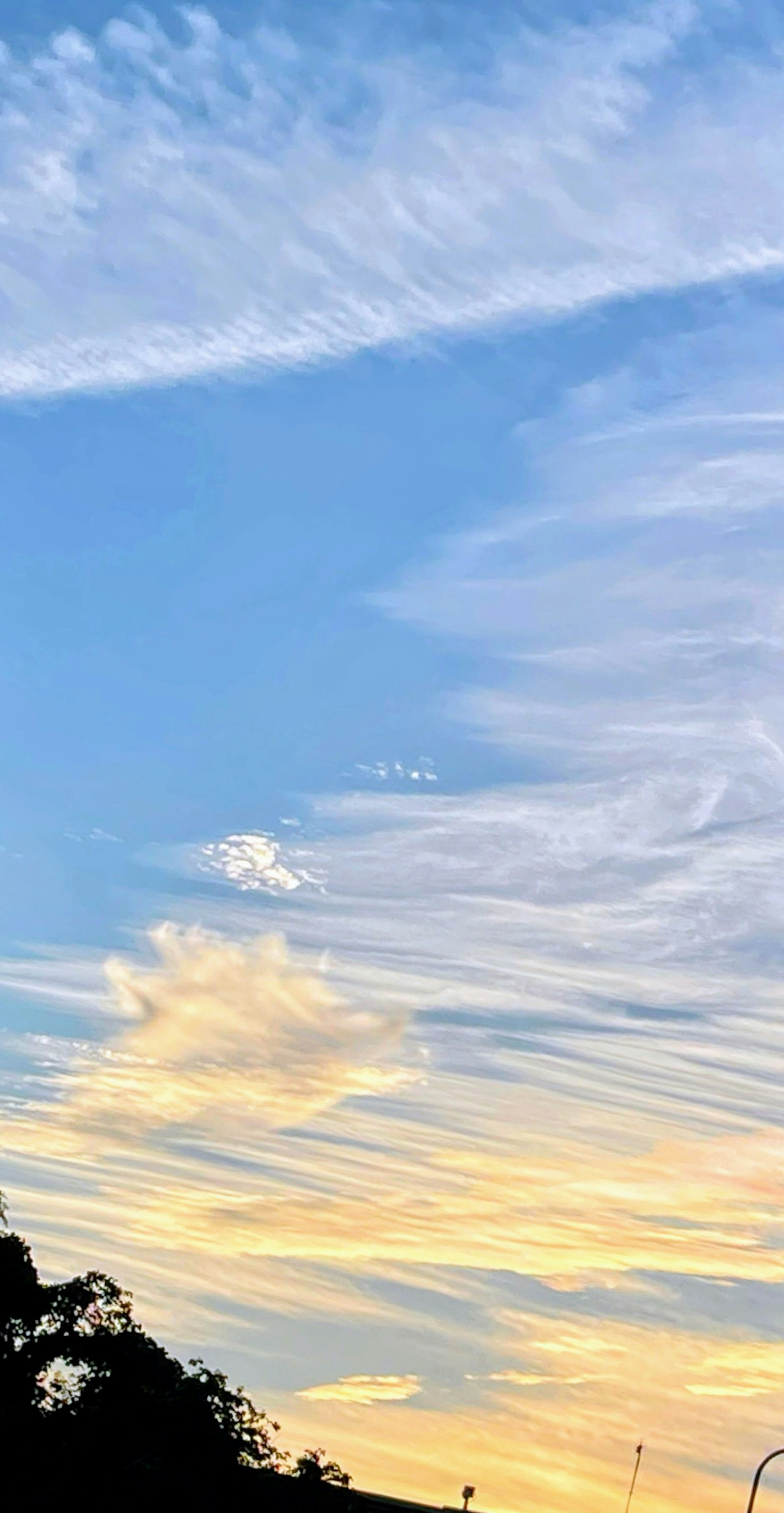 Blauer Himmel mit weißen Wolken und orangefarbenem Sonnenuntergang