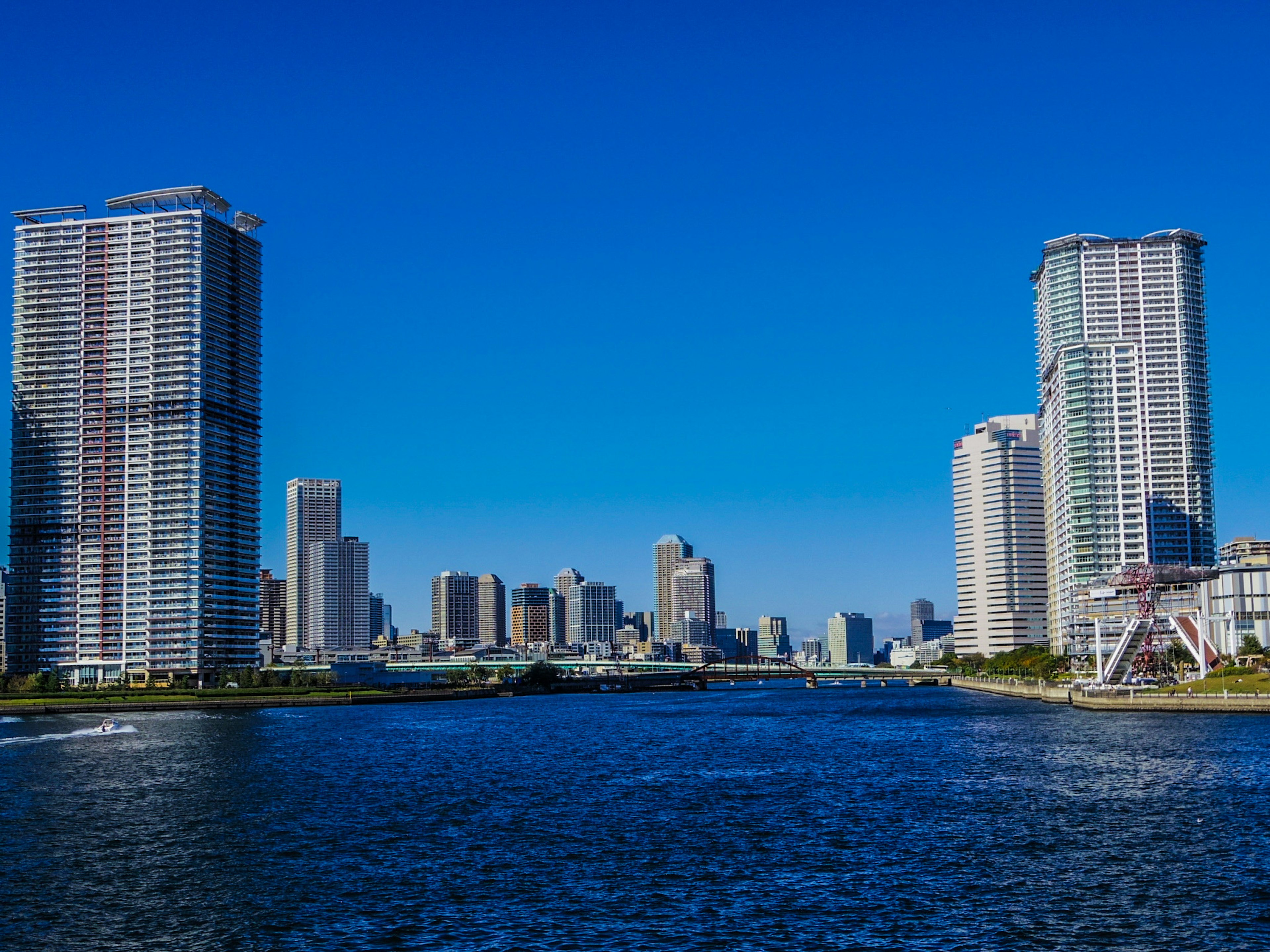 Skyline di città con grattacieli e fiume sotto un cielo blu