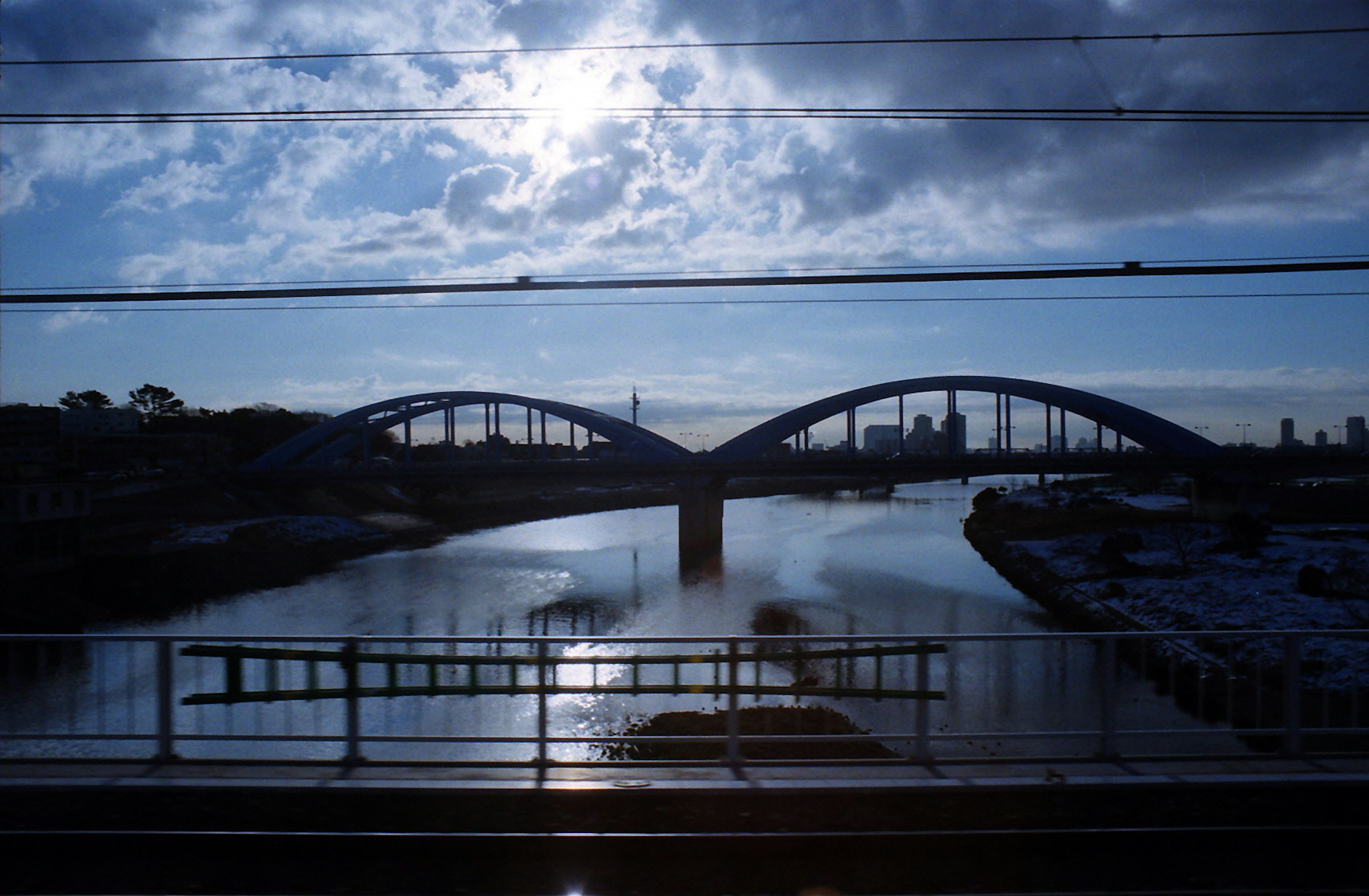 สะพานโค้งที่สวยงามเหนือแม่น้ำสงบใต้ท้องฟ้าสีฟ้าพร้อมเมฆ