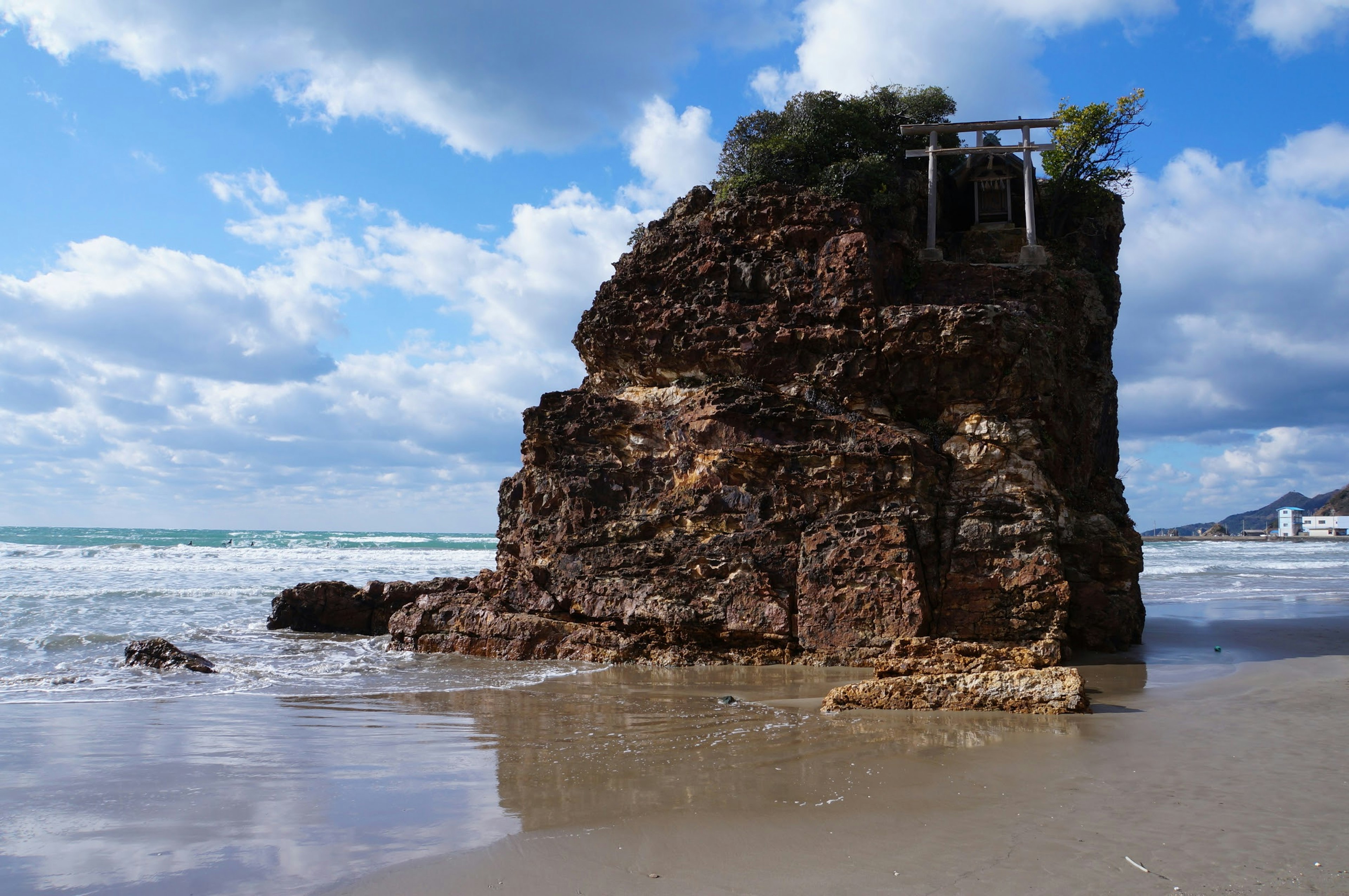 Formazione rocciosa sulla spiaggia con cielo blu e nuvole