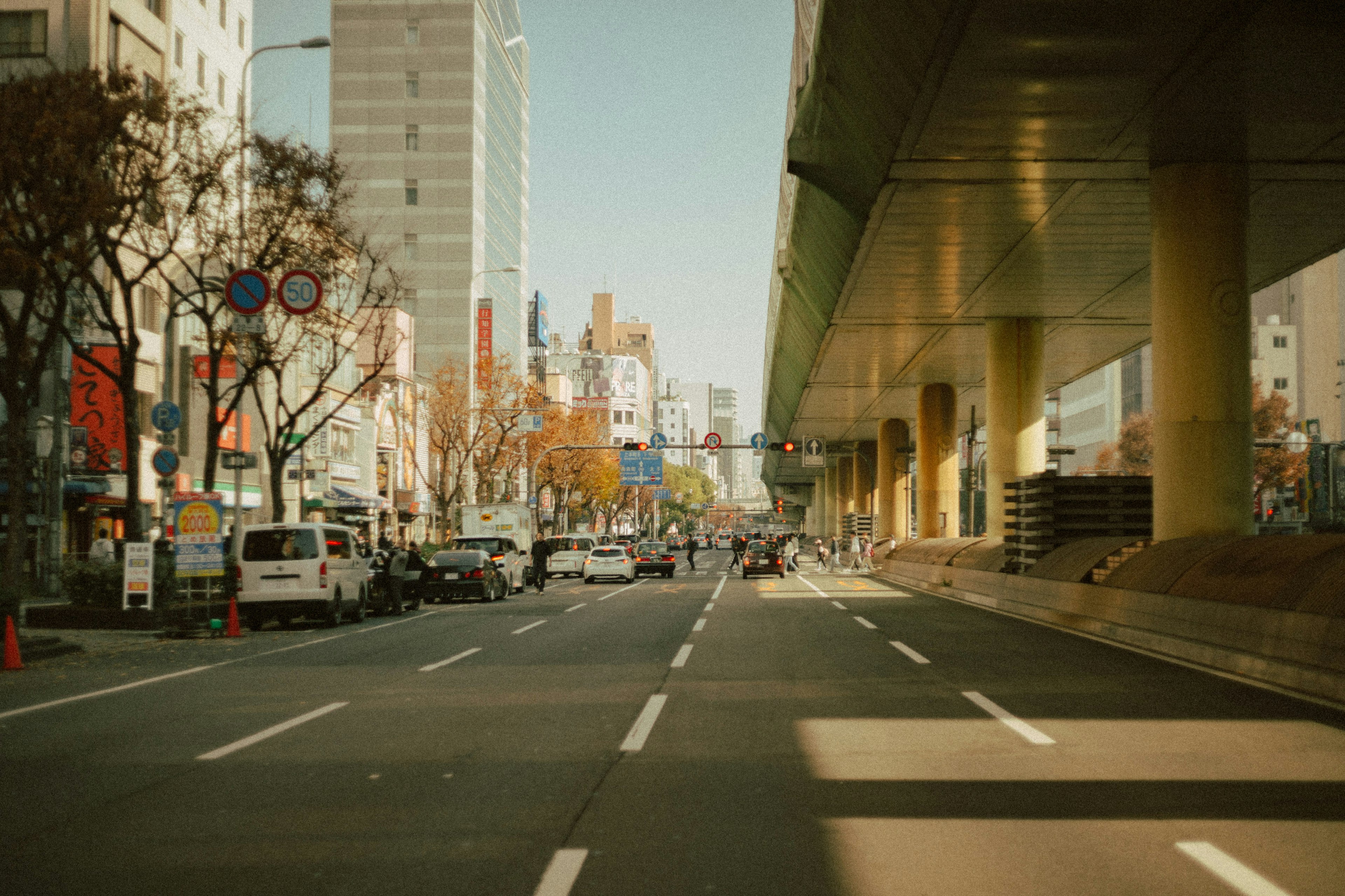 Paysage urbain avec une rue sous une autoroute élevée présentant des bâtiments voisins et des voitures garées