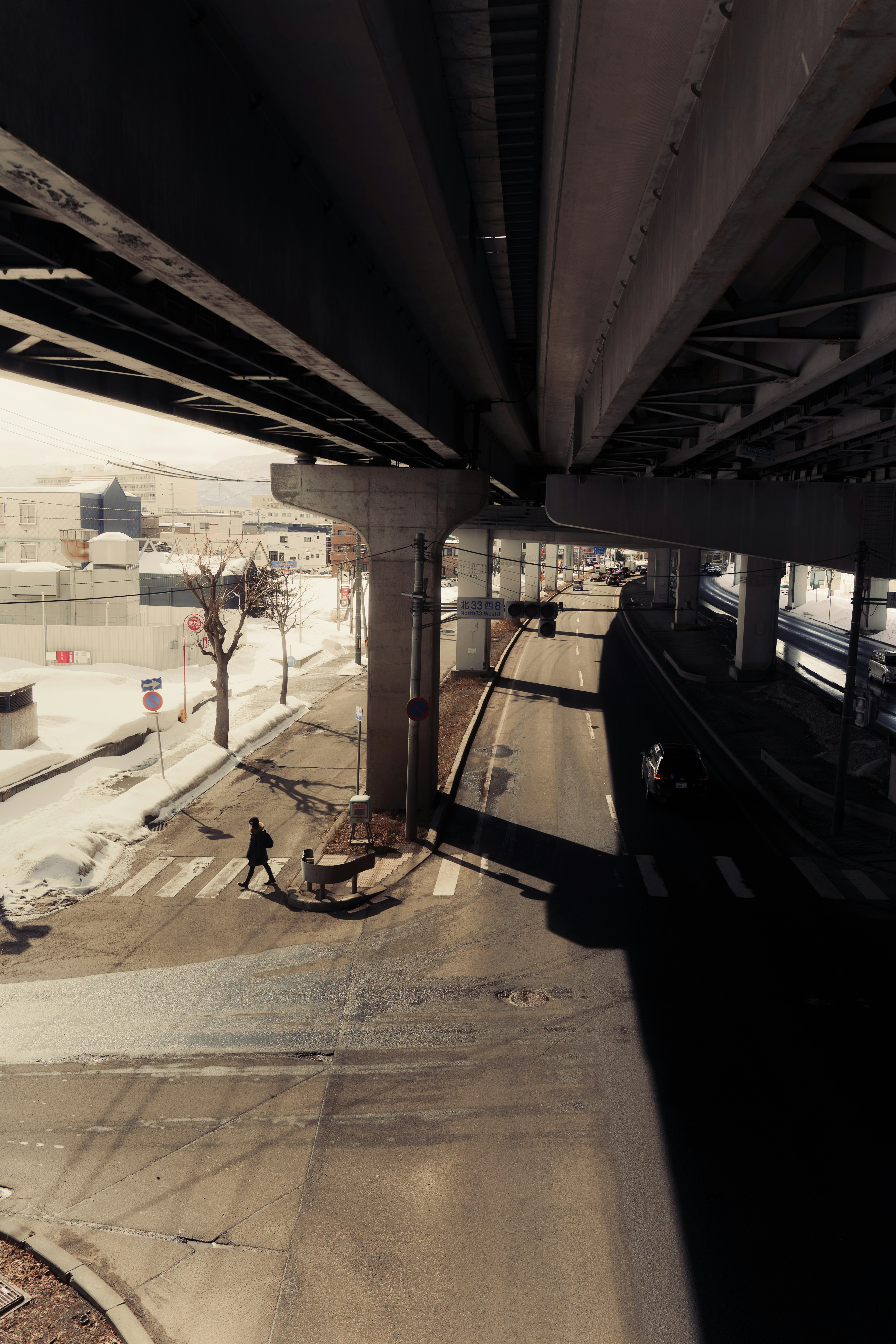 Urban scene showing a road under an overpass with pedestrian silhouettes