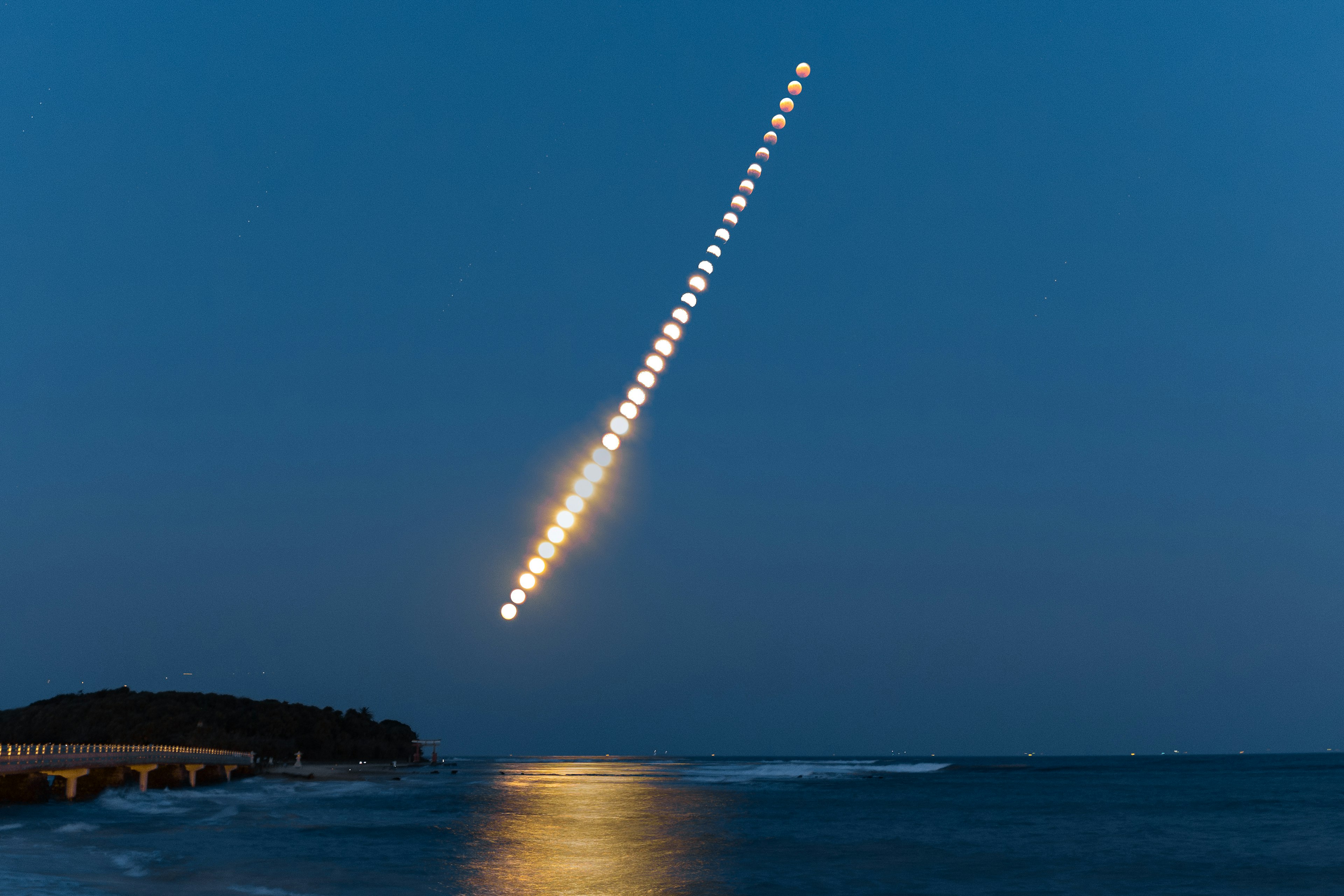 Streak of moon phases over the ocean at twilight