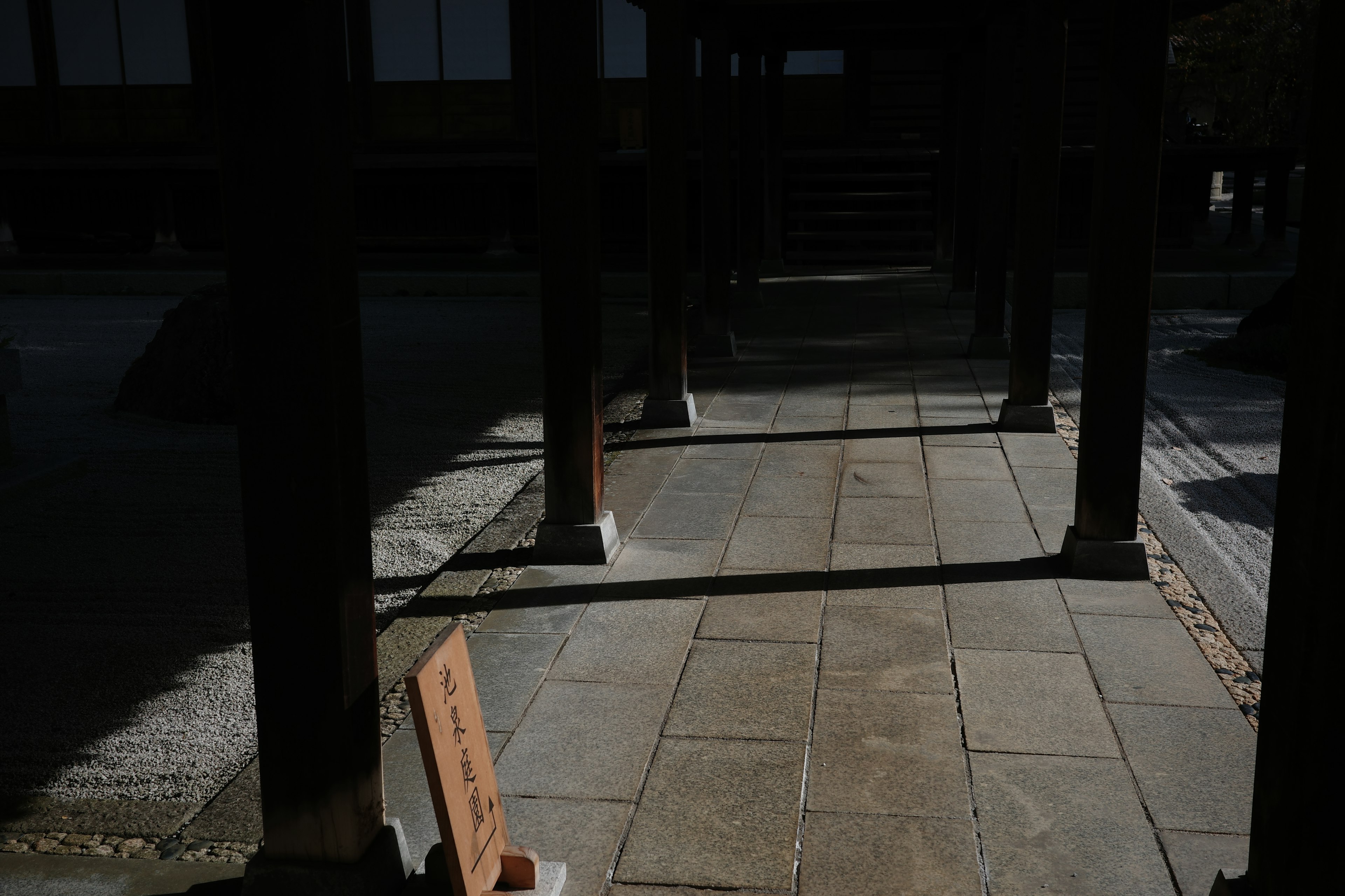 Contrast of light and shadow on a stone pathway under wooden pillars