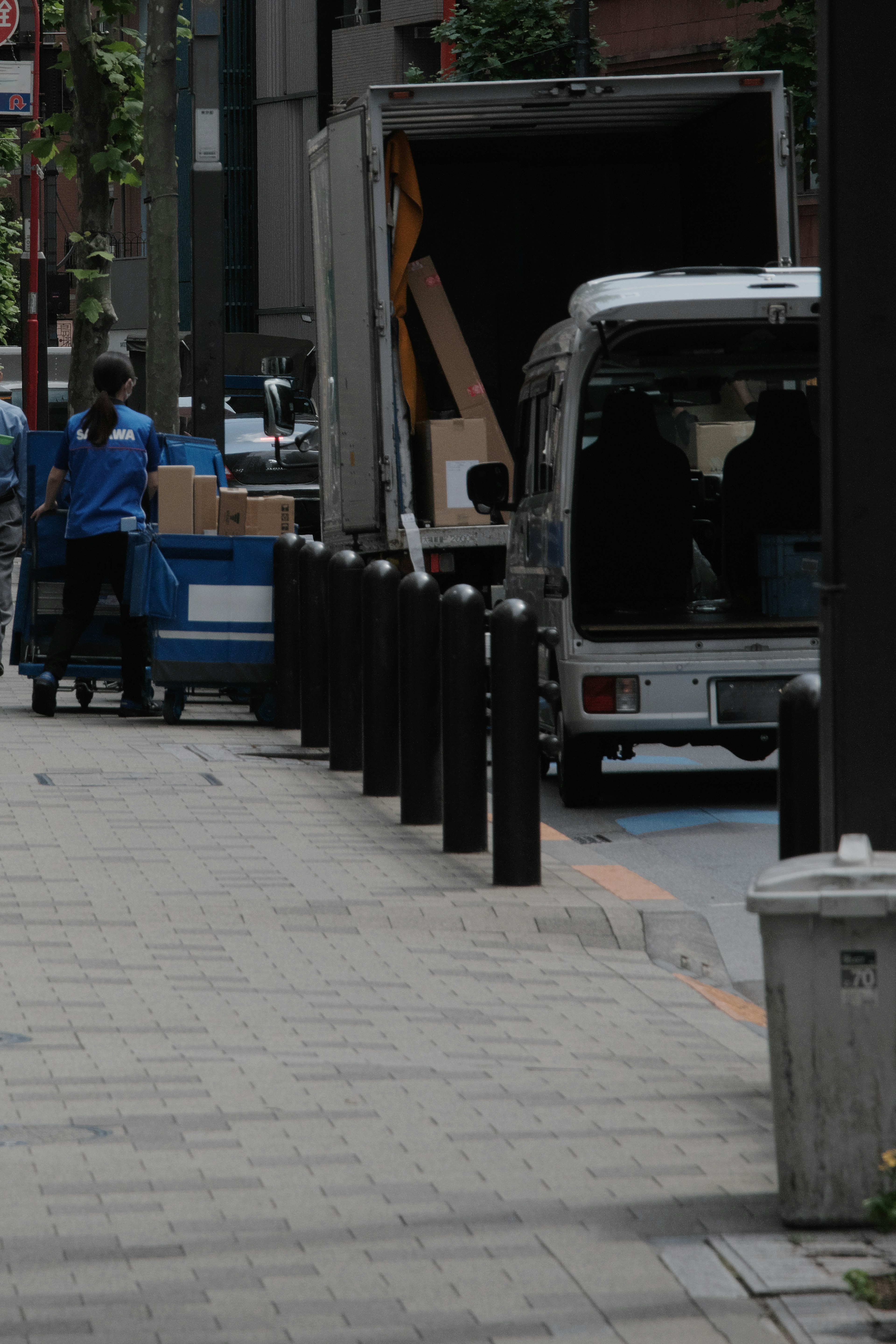 Un trabajador con uniforme azul está manipulando cajas cerca de un camión de entrega