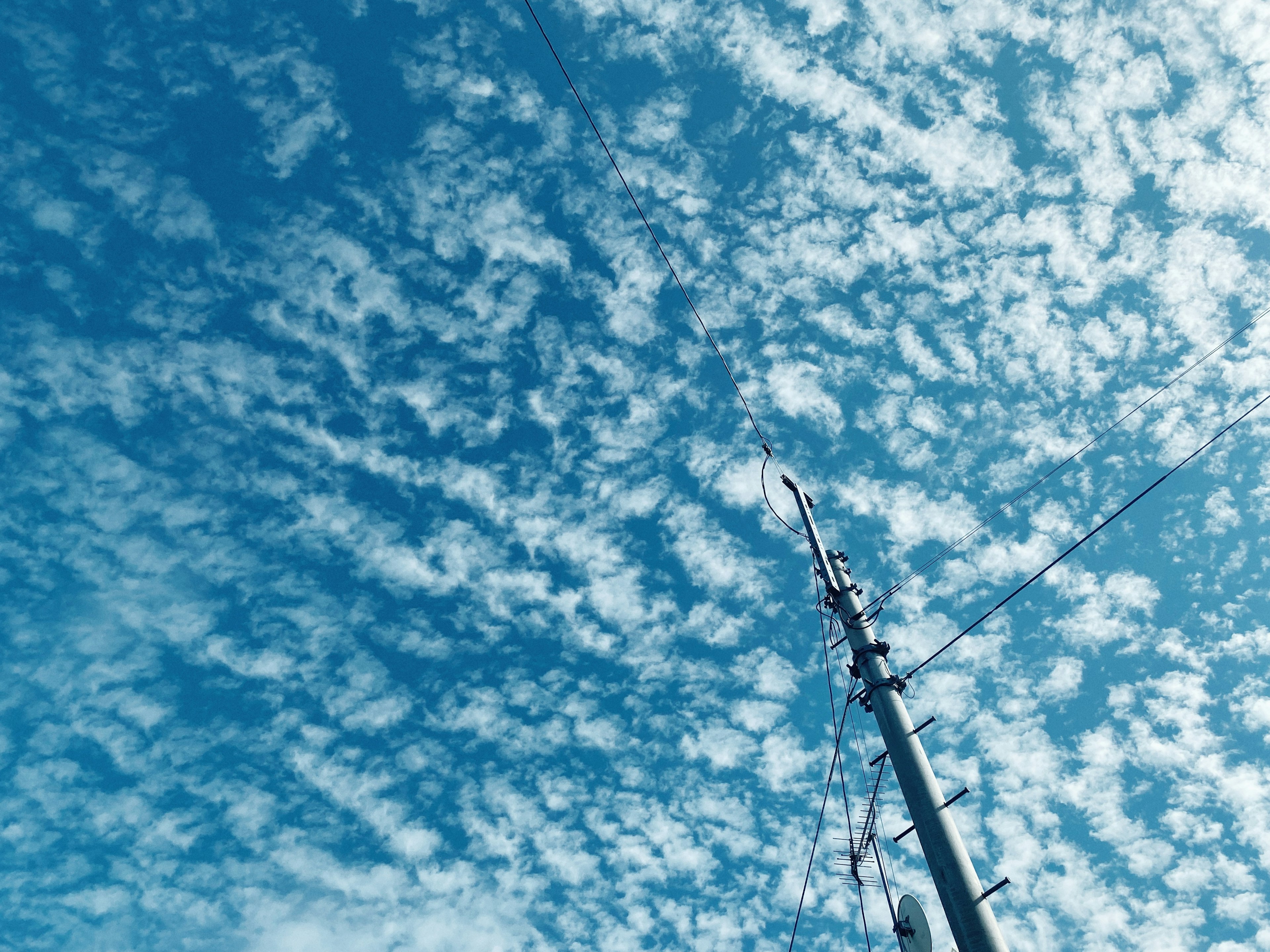 Cielo blu pieno di nuvole bianche e un'antenna alta