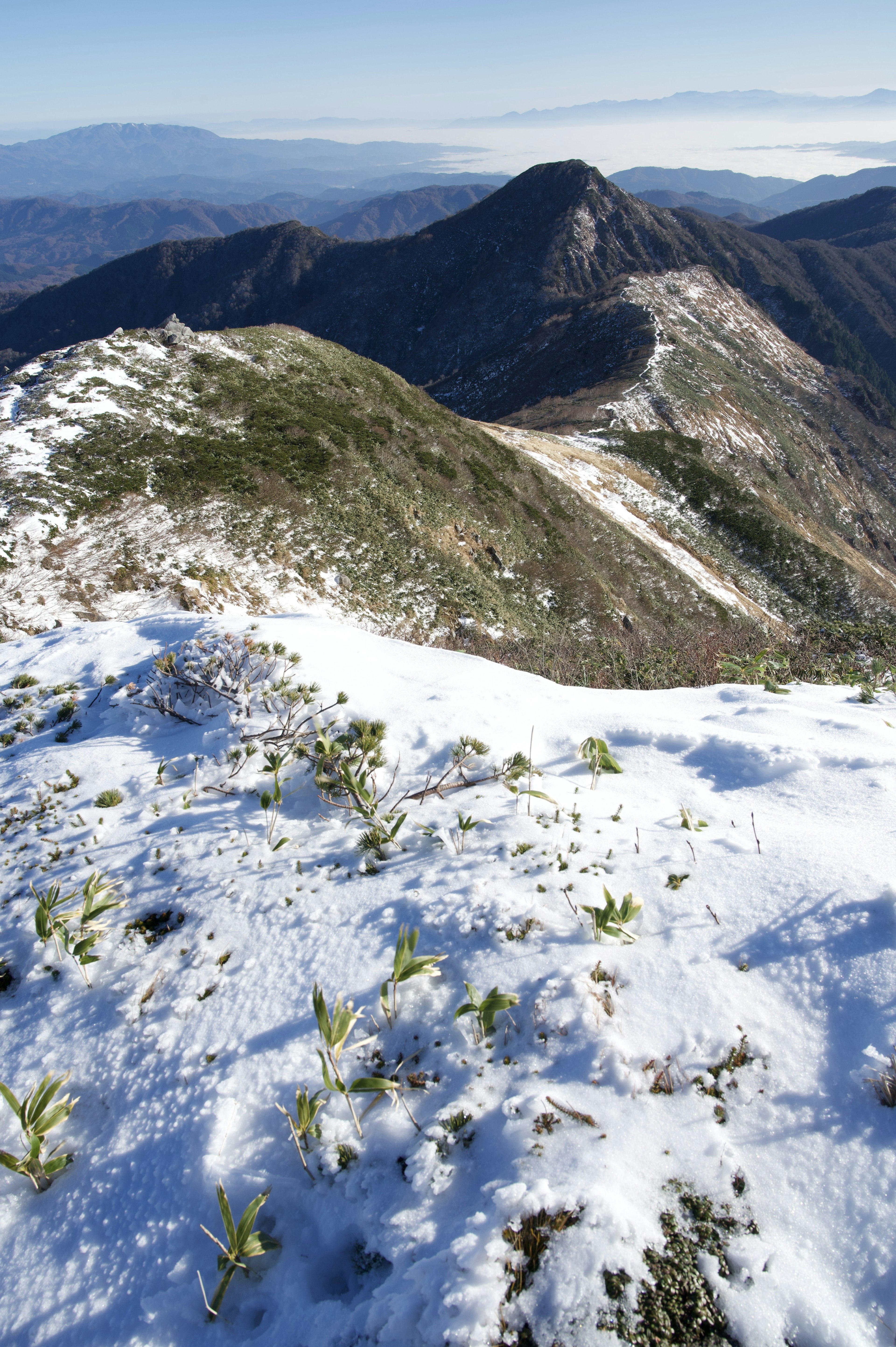 雪覆蓋的山脈景觀，遠處的山峰和晴朗的藍天