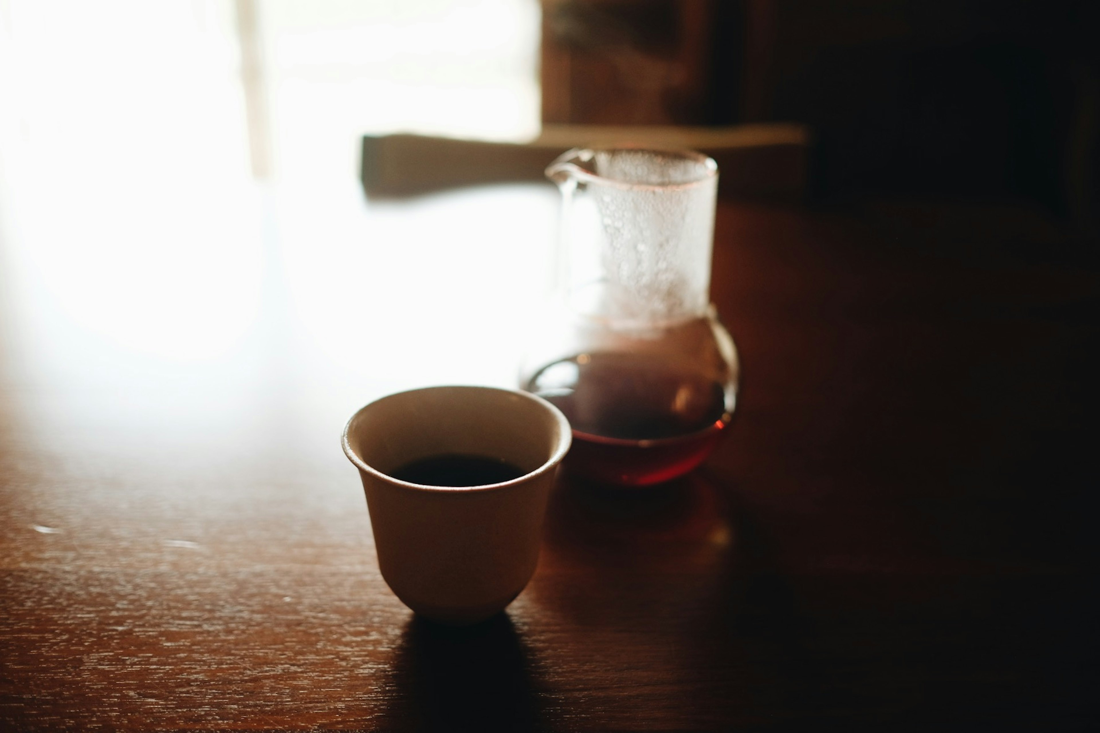 A cup of coffee and a flask on a wooden table