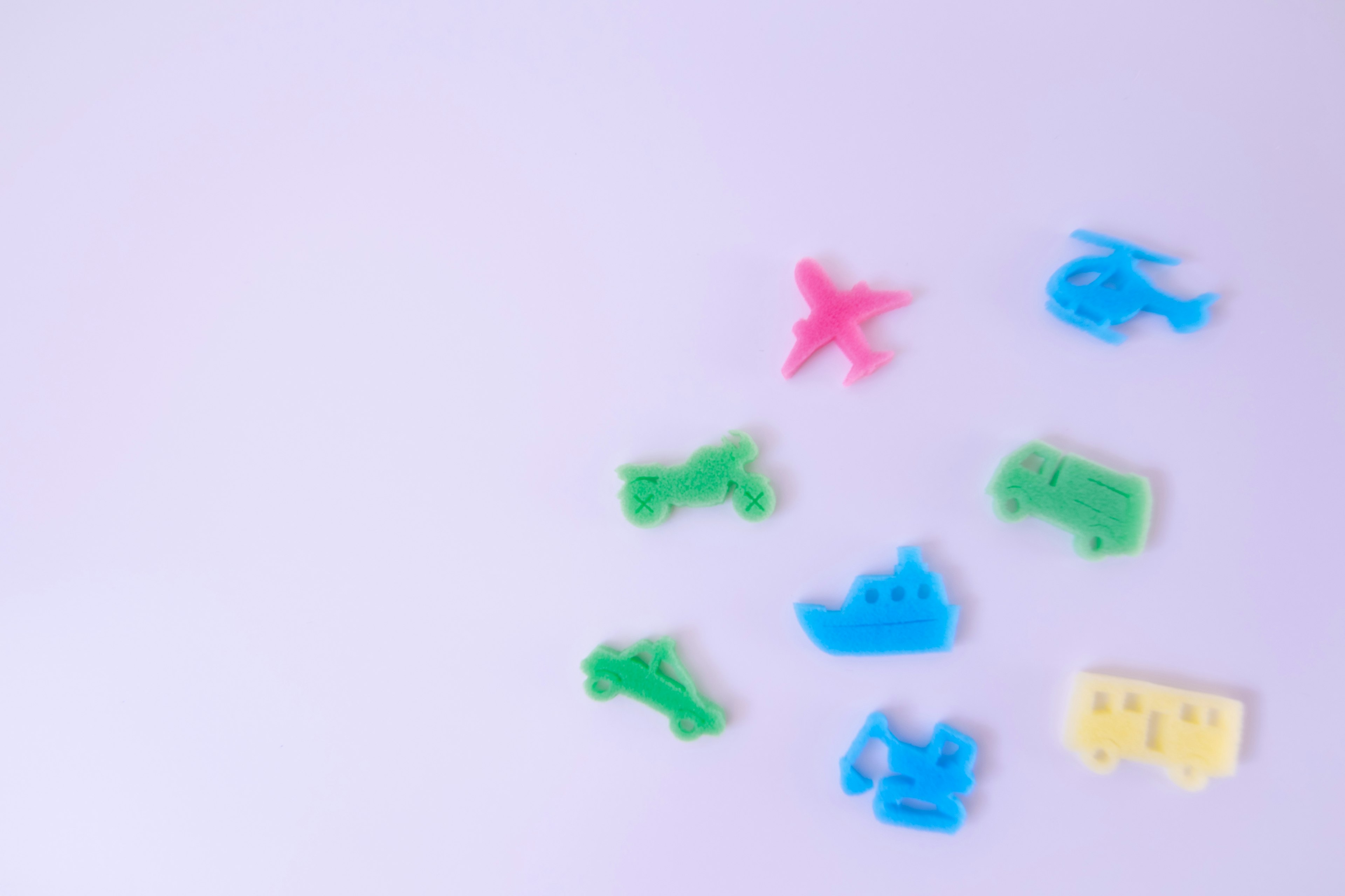 Colorful plastic vehicle-shaped objects scattered on a white background