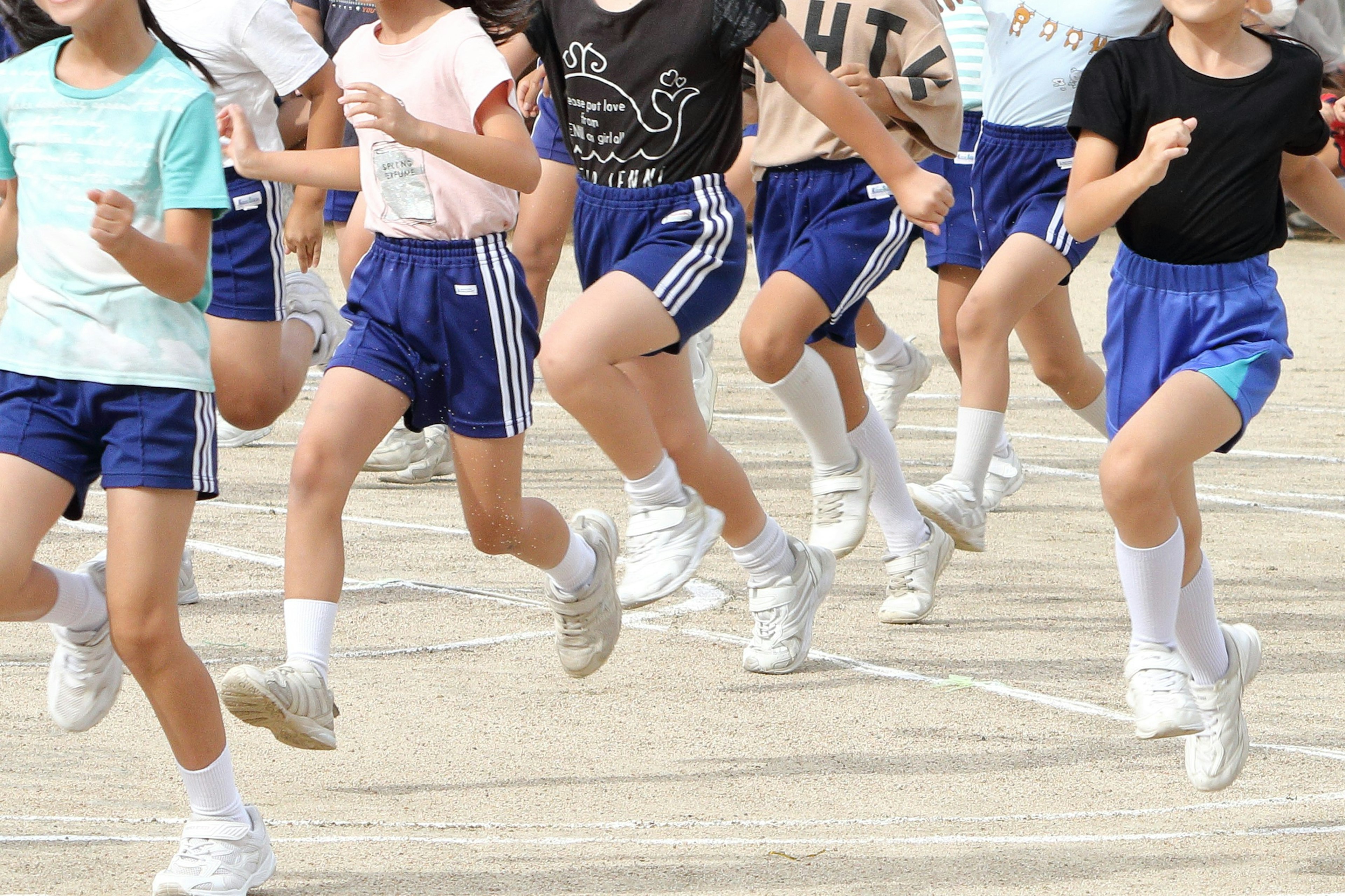 Groupe d'enfants courant sur un terrain de jeu portant des shorts bleus et des chaussettes blanches