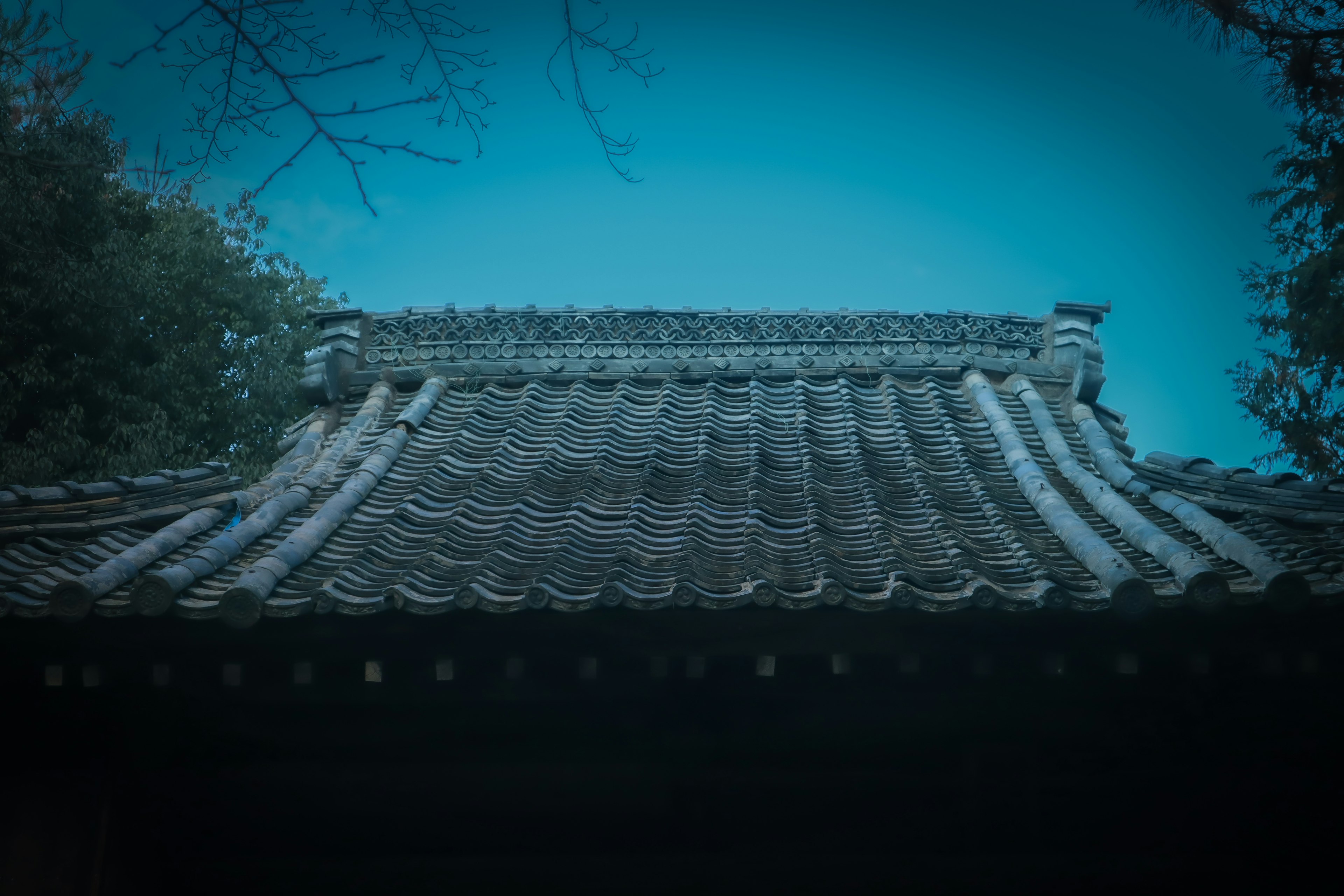 Detailed view of an ancient tiled roof under a blue sky