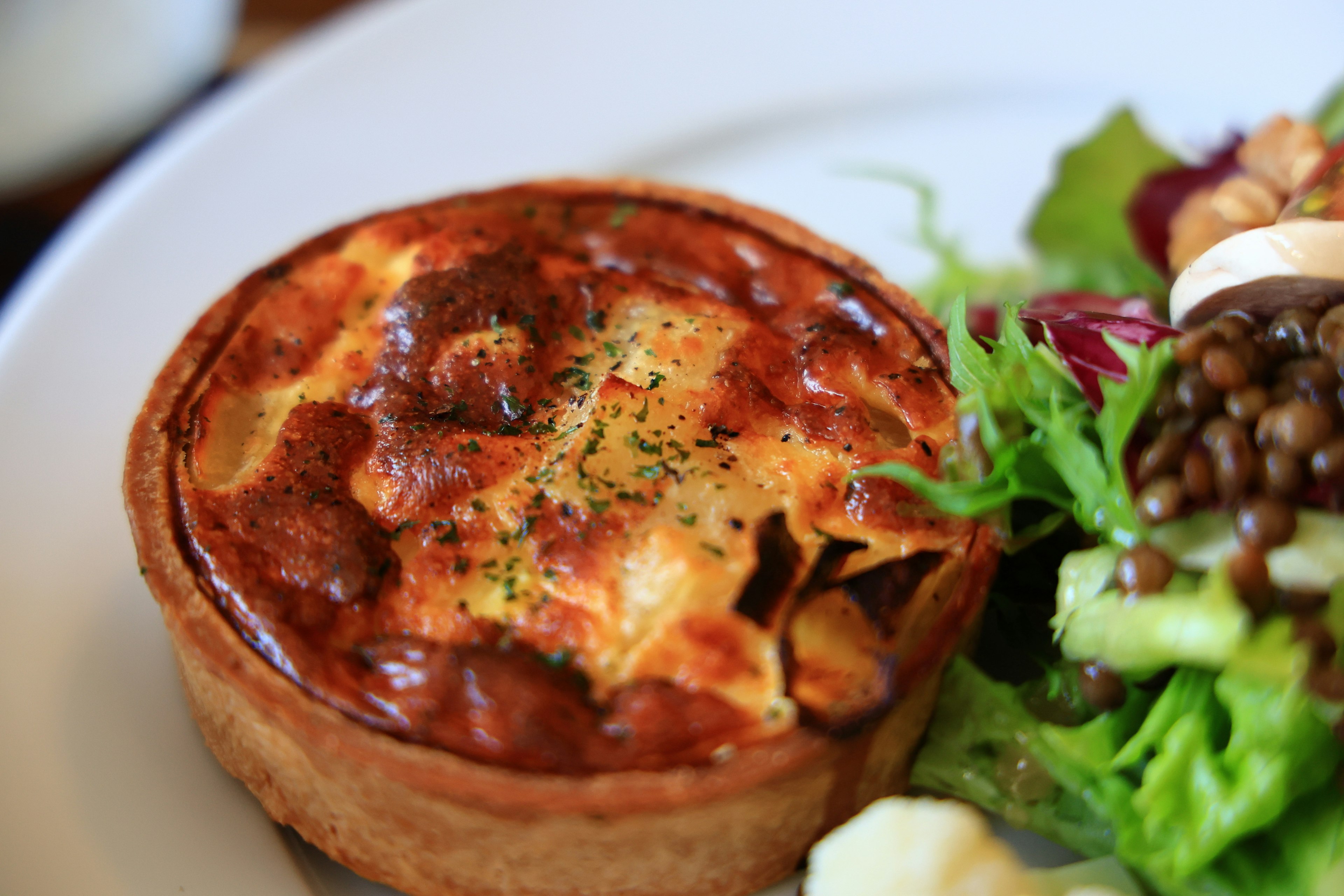 Golden-brown quiche next to a fresh salad