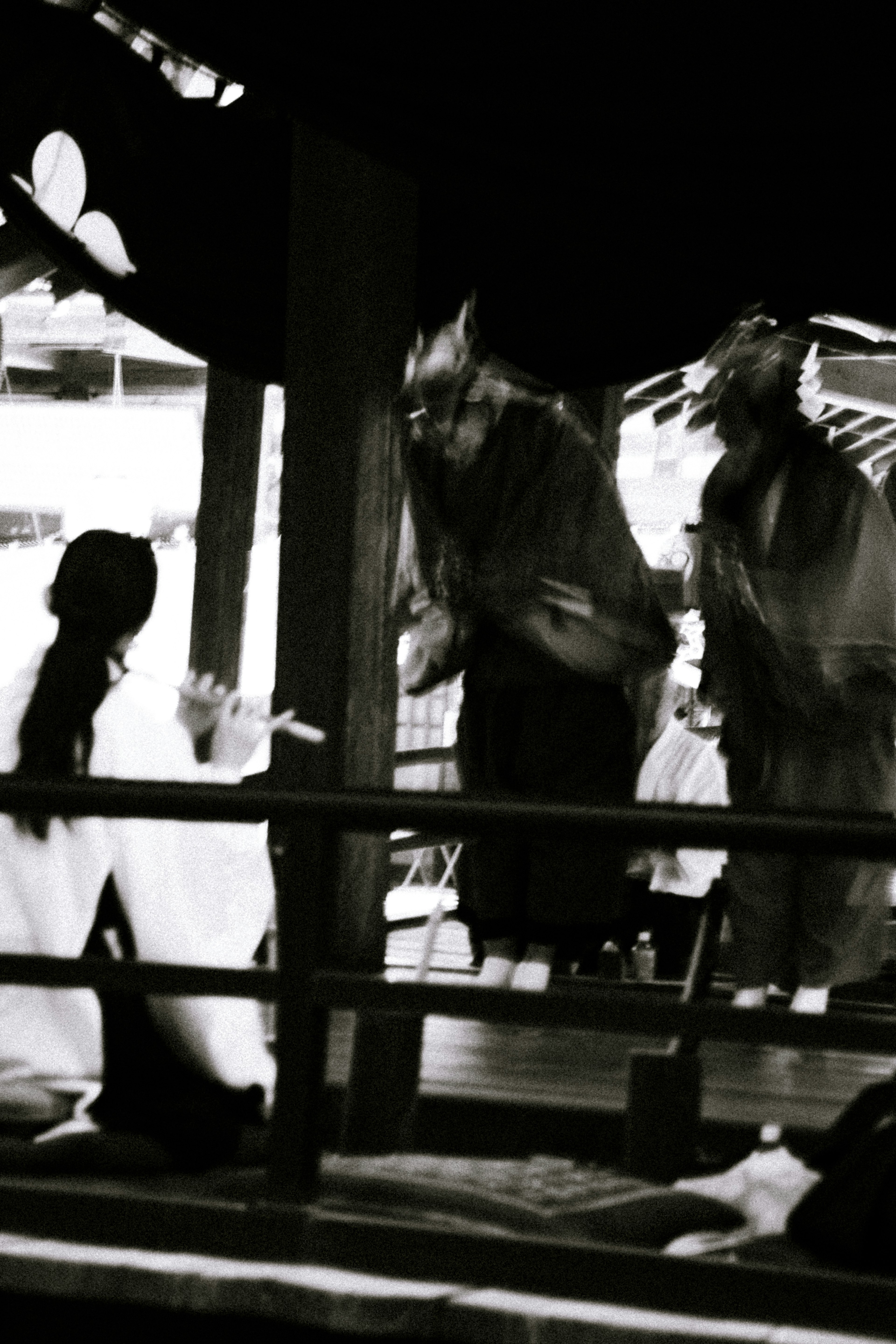 Two masked performers dancing on a black and white stage with a woman in white attire