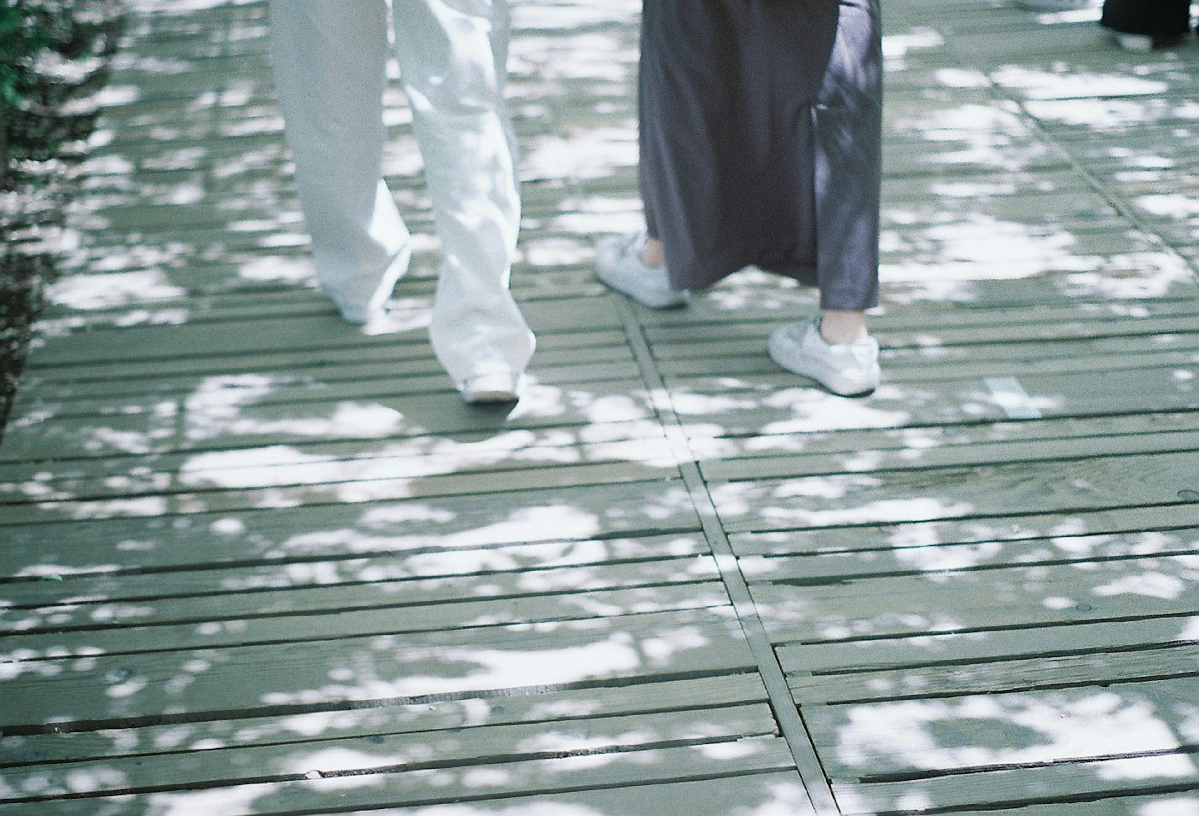 Pieds de deux personnes sur un chemin en bois avec de jolis motifs d'ombre