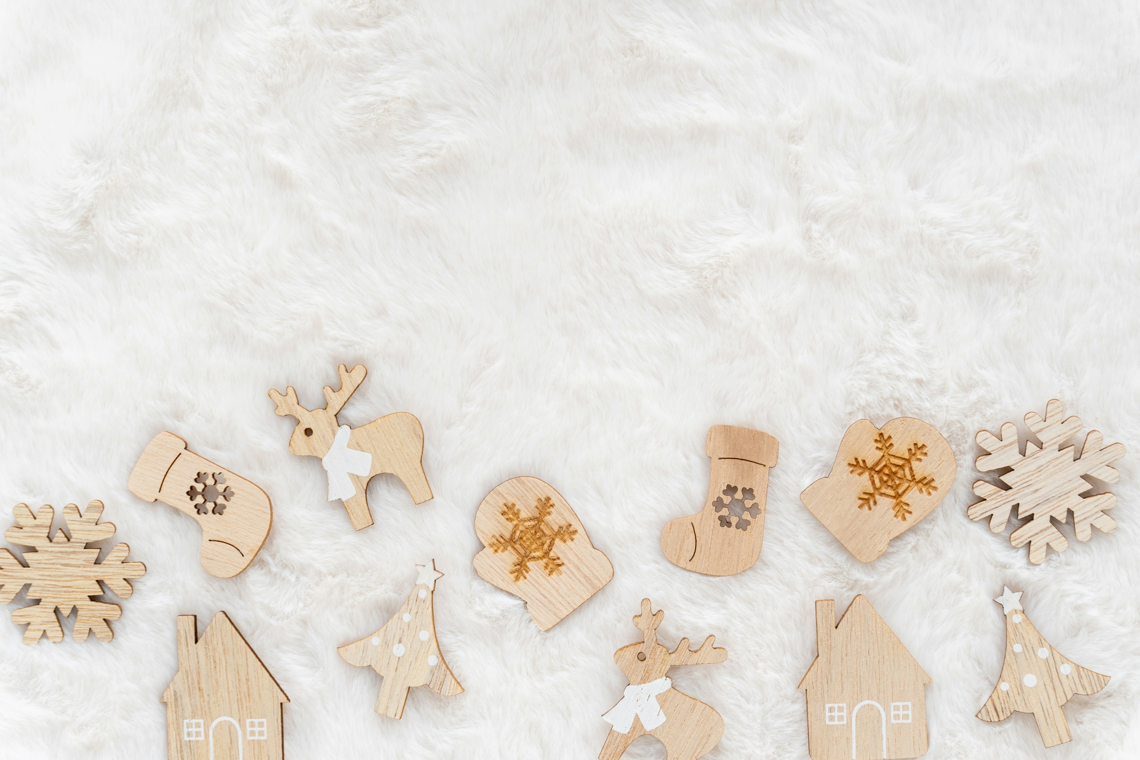 A set of wooden Christmas ornaments arranged on a white fur background