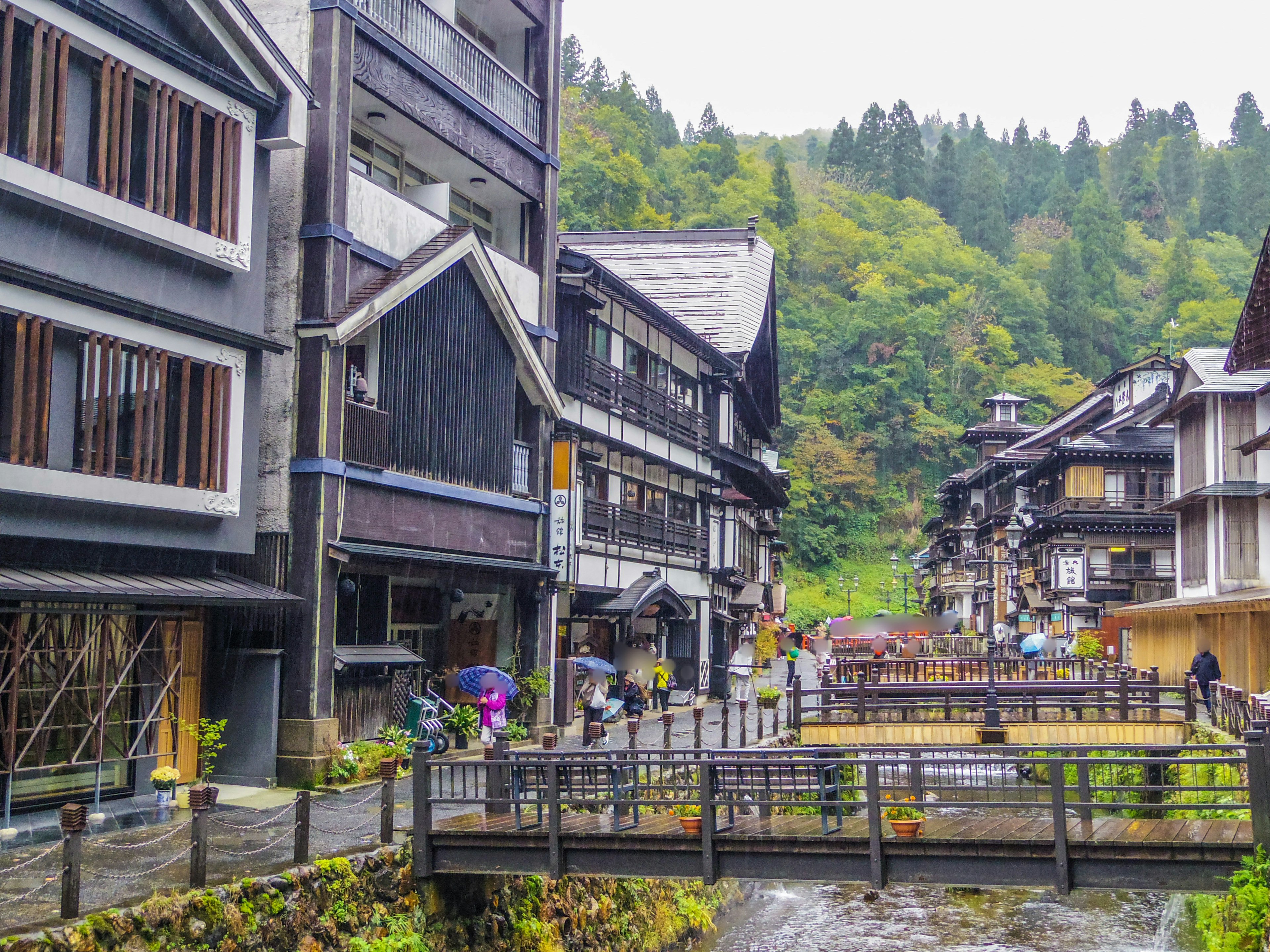 Scenic view of a traditional hot spring town with wooden buildings and a stream