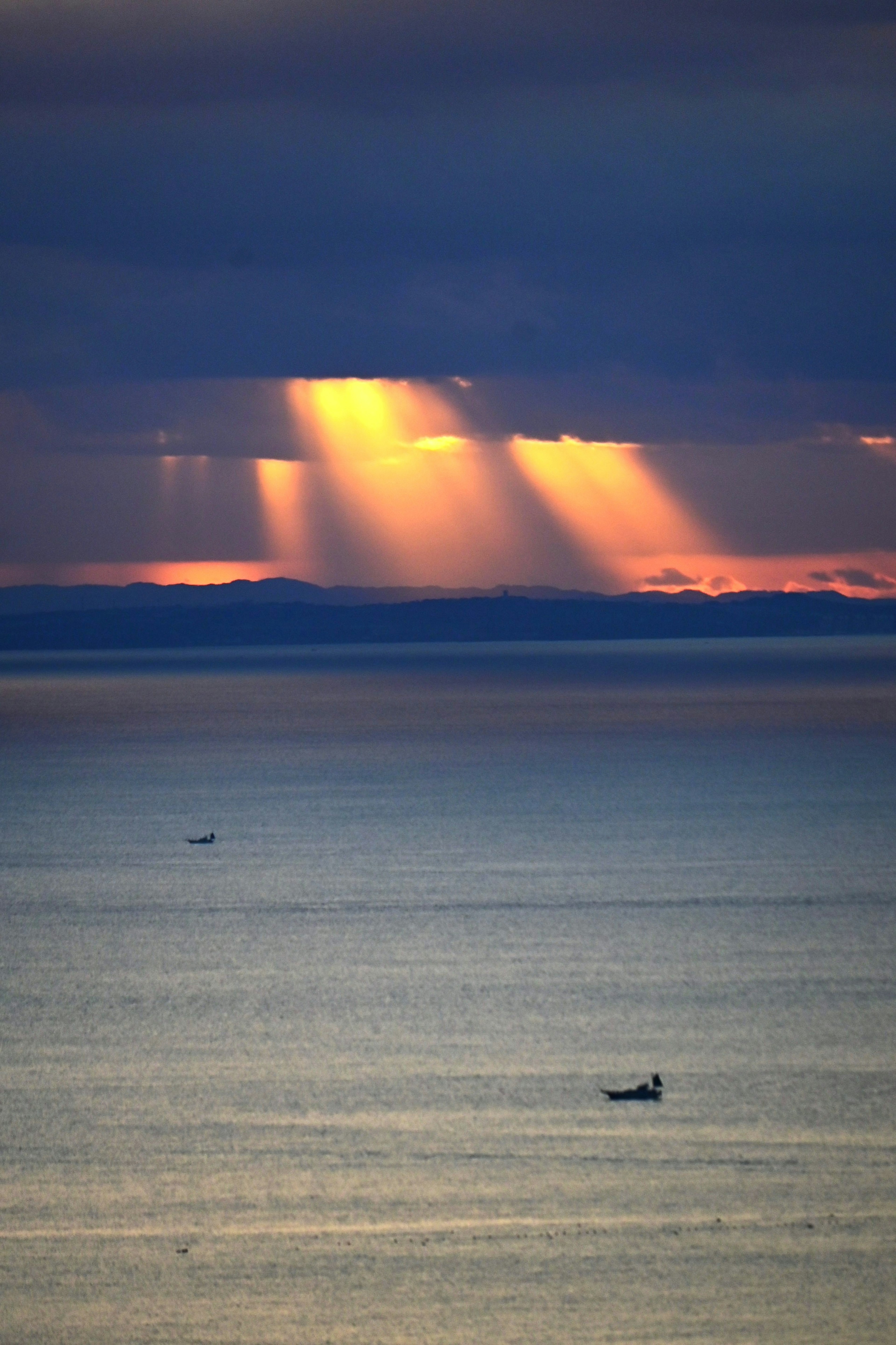 海上日落，光束穿透雲層