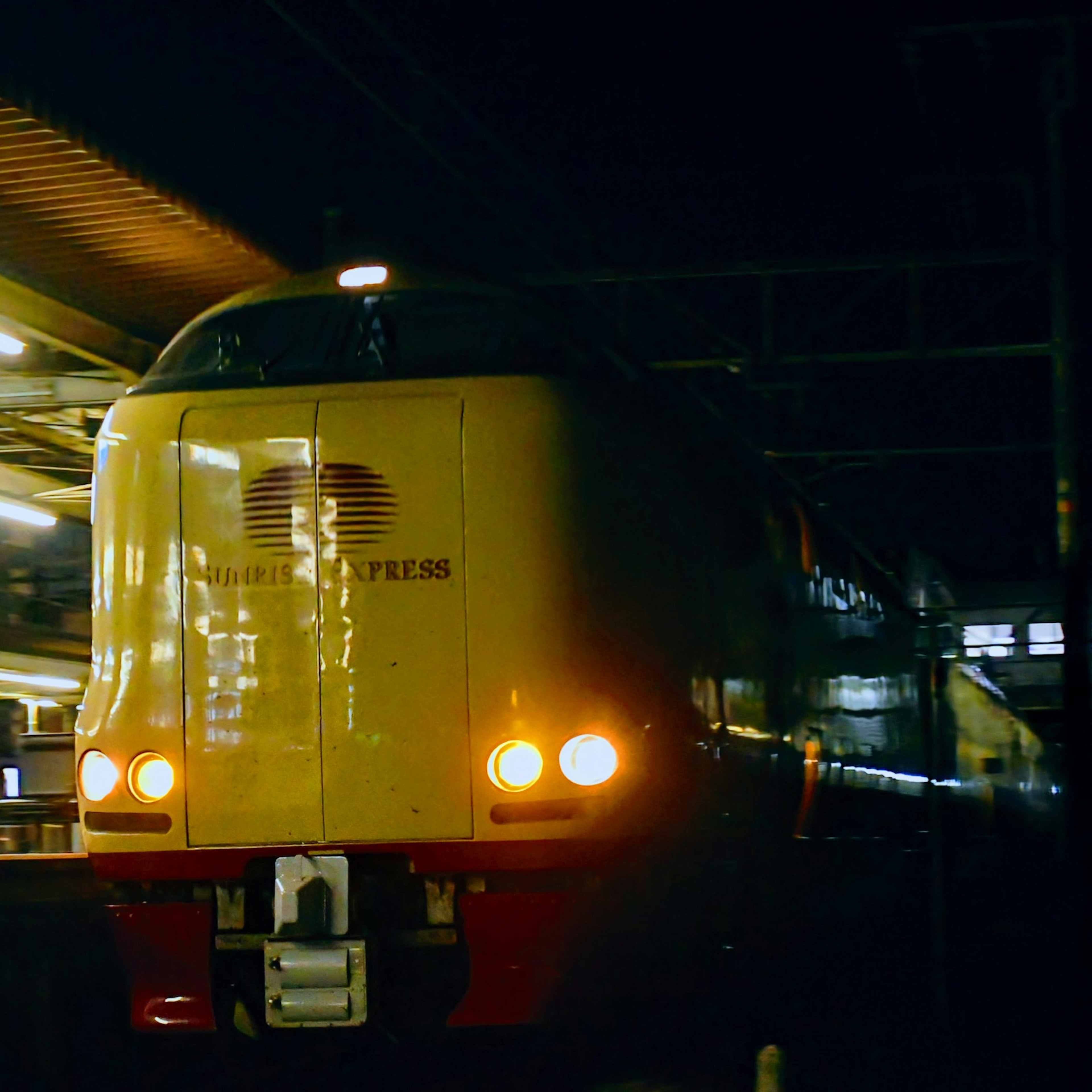 夜の駅に停車中の黄色い特急列車