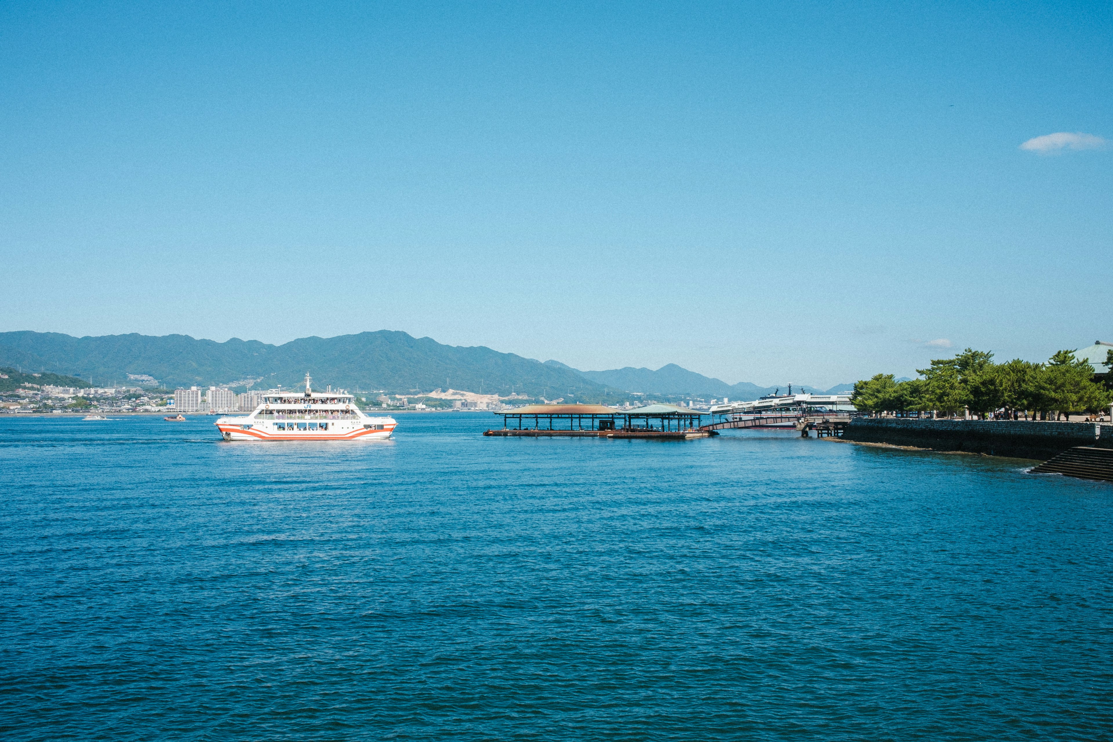 Ferry sailing on blue water with mountains in the background