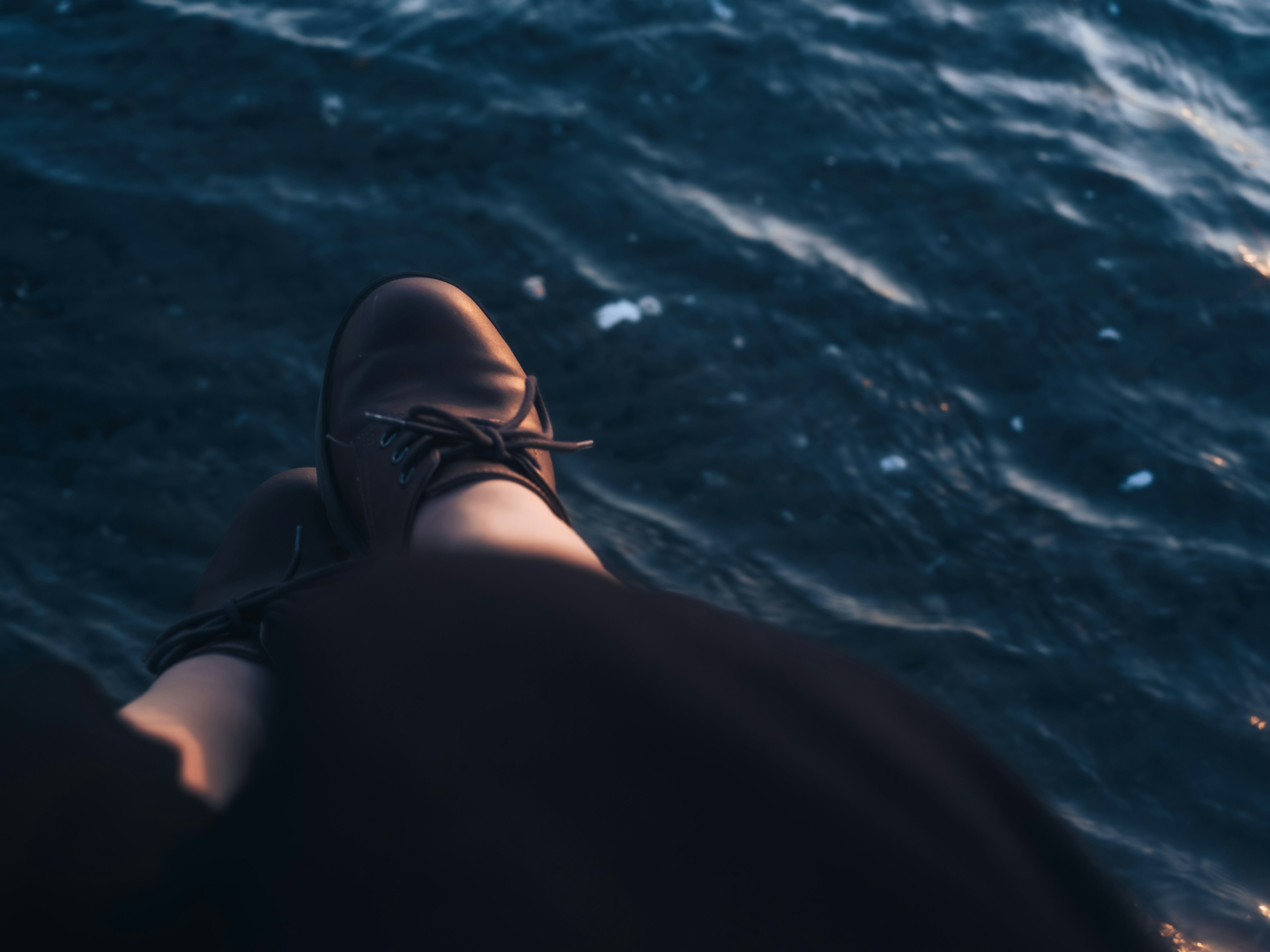 Scarpe e piedi penzoloni sopra l'acqua