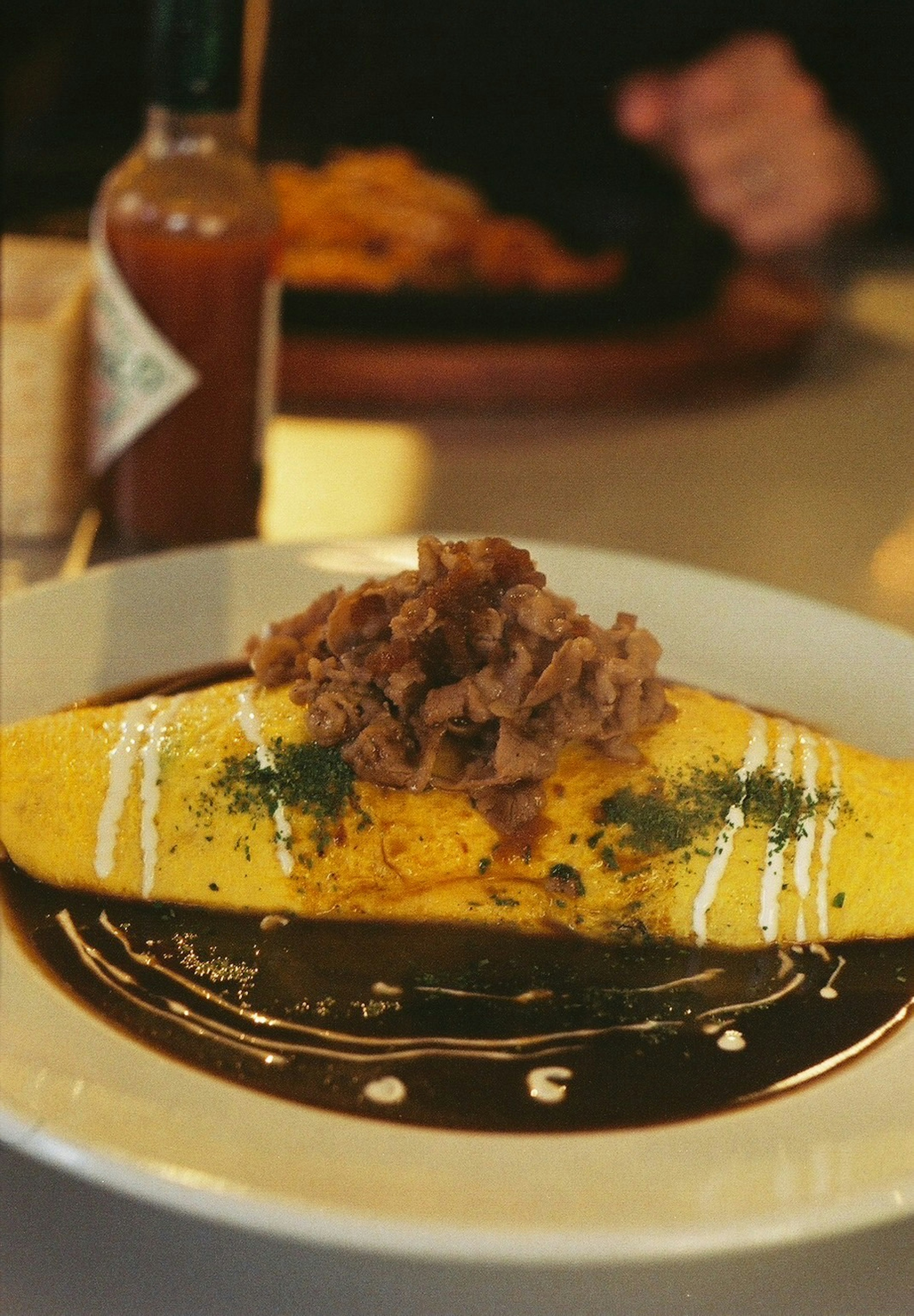 Omelet kuning yang diberi daging dan saus di piring putih