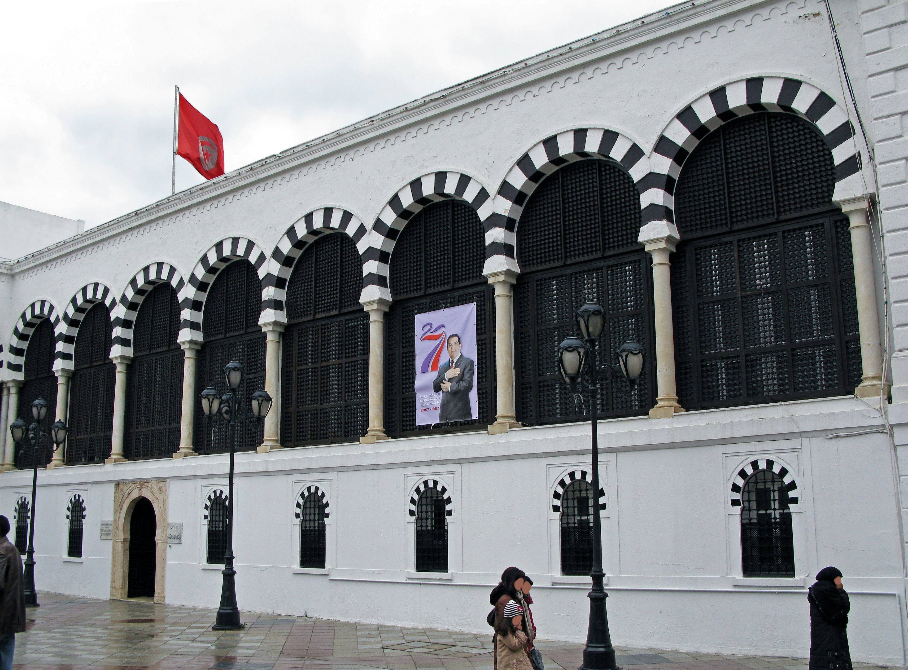 Edificio con arcos de rayas blancas y negras Exterior blanco con grandes ventanas Bandera turca exhibida sobre las ventanas