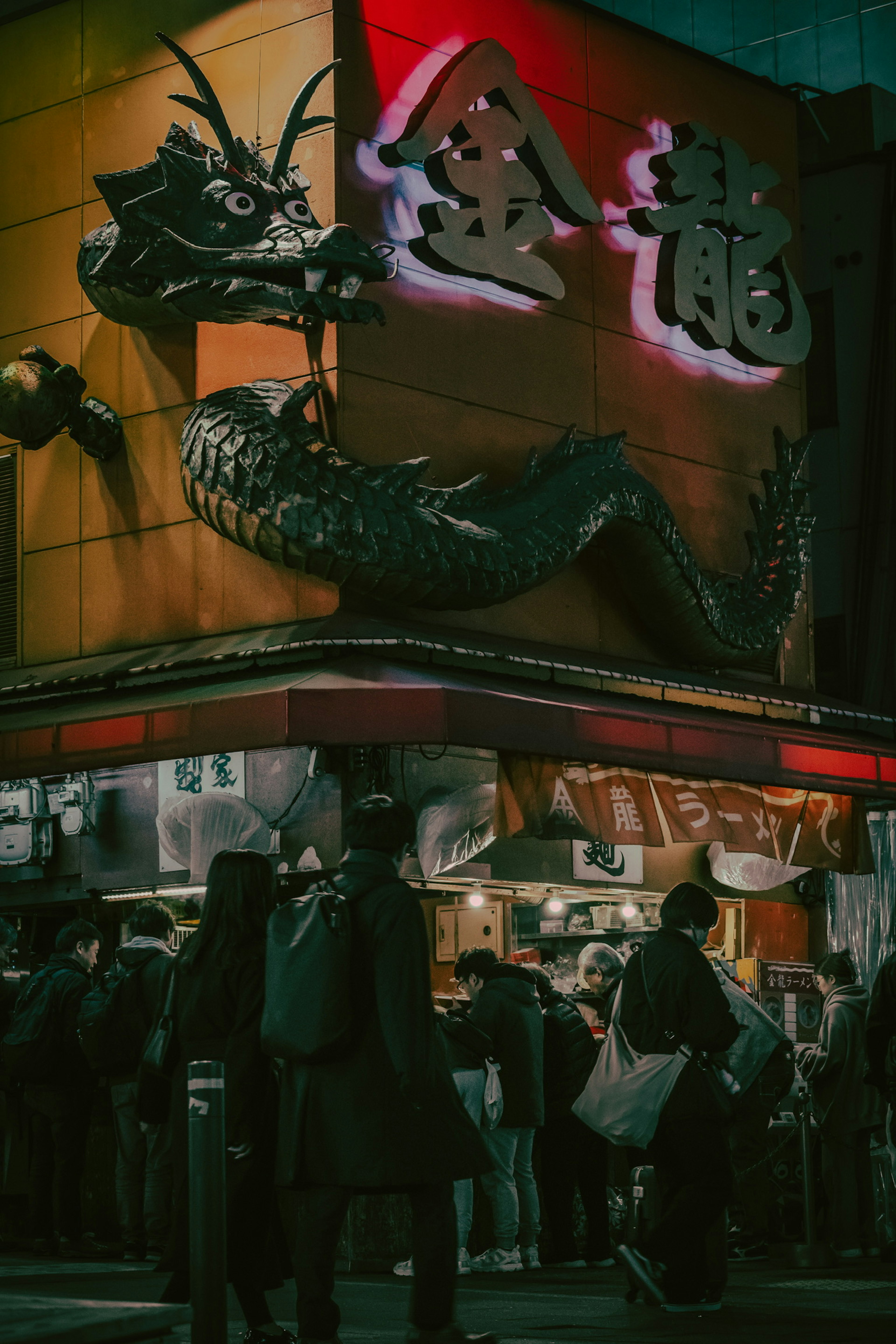 夜の街に浮かぶ金龍の看板と行列の人々