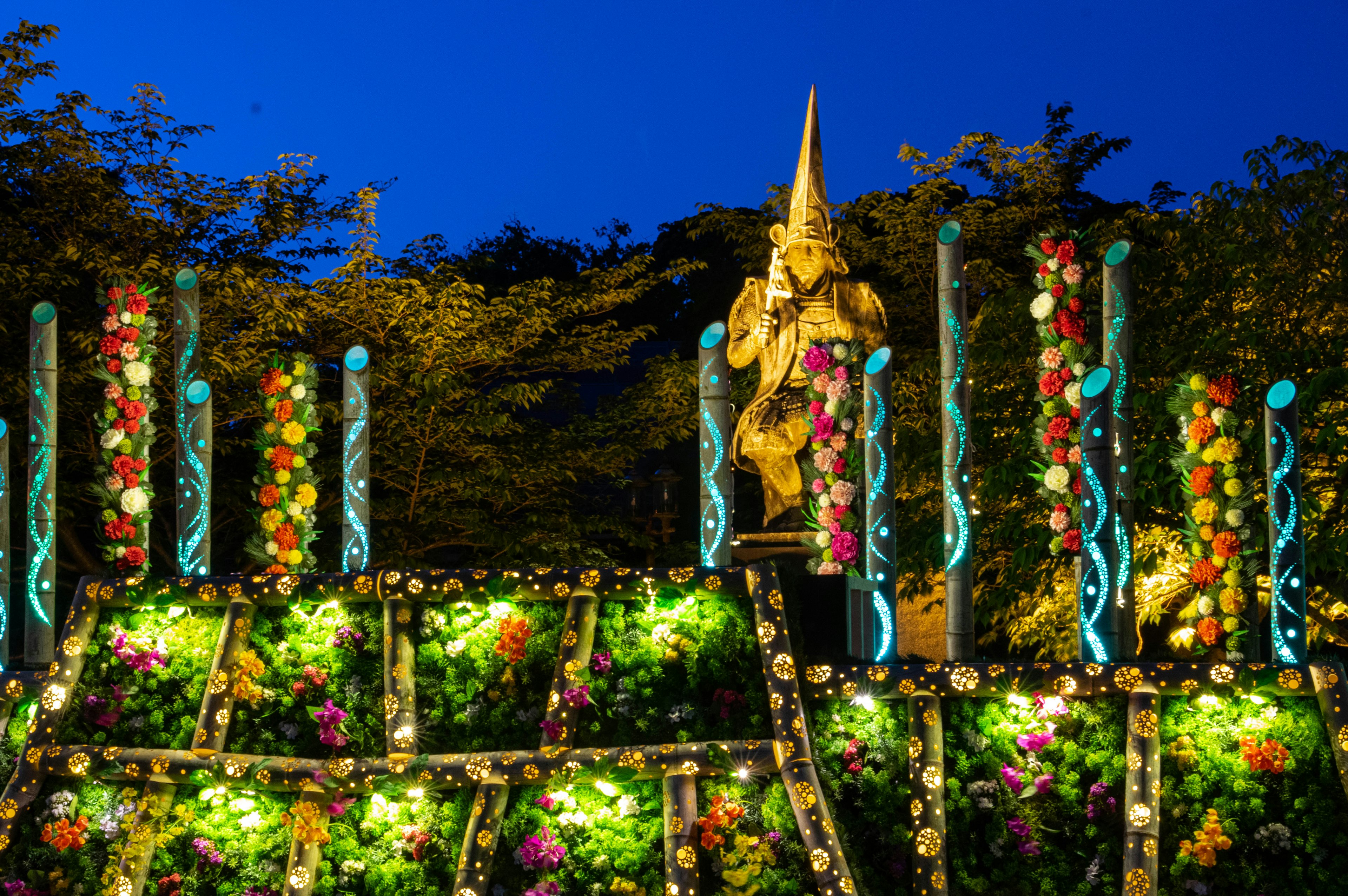 Decorated statue and flower arrangements under a blue night sky