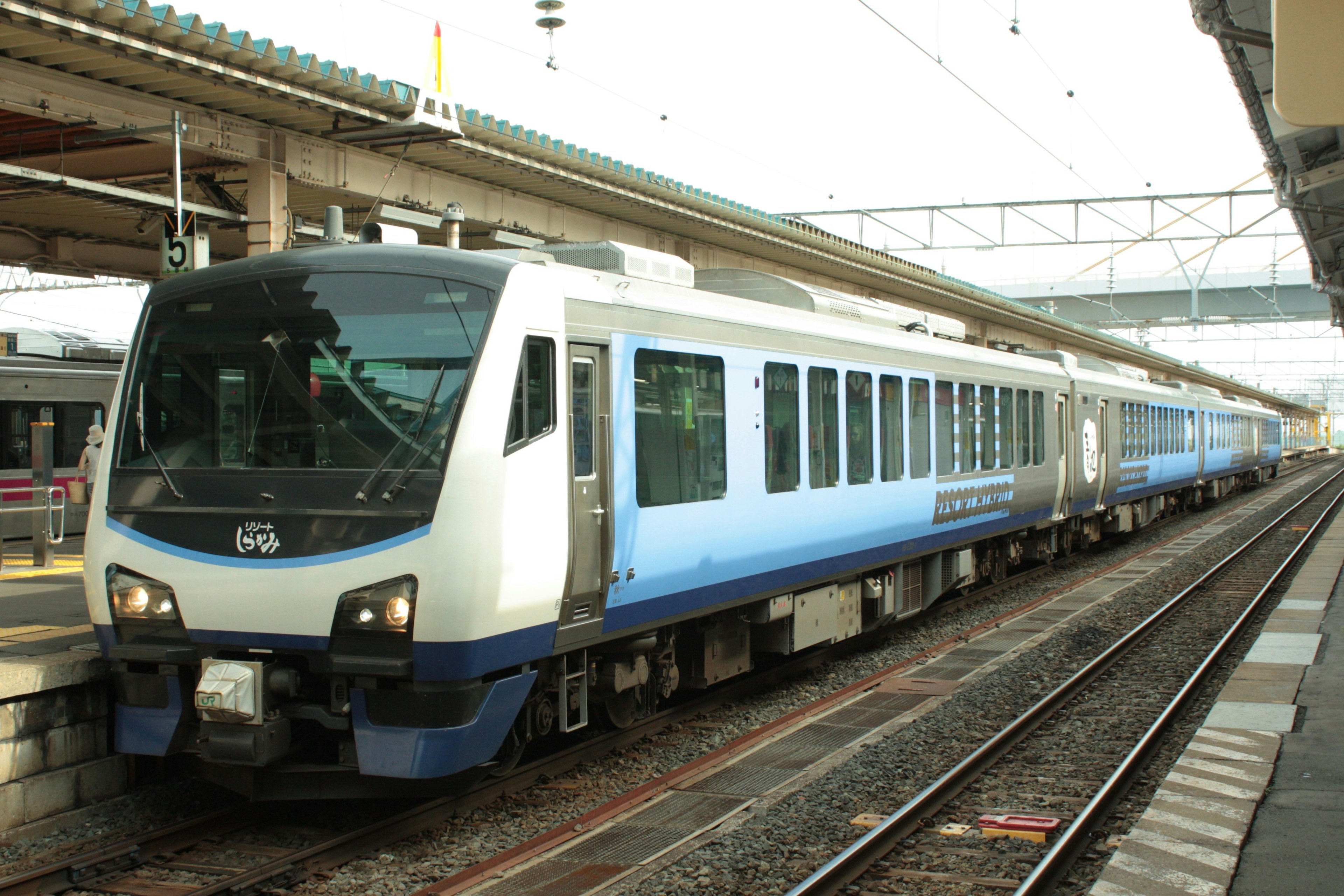 Kereta komuter biru dan putih berhenti di stasiun