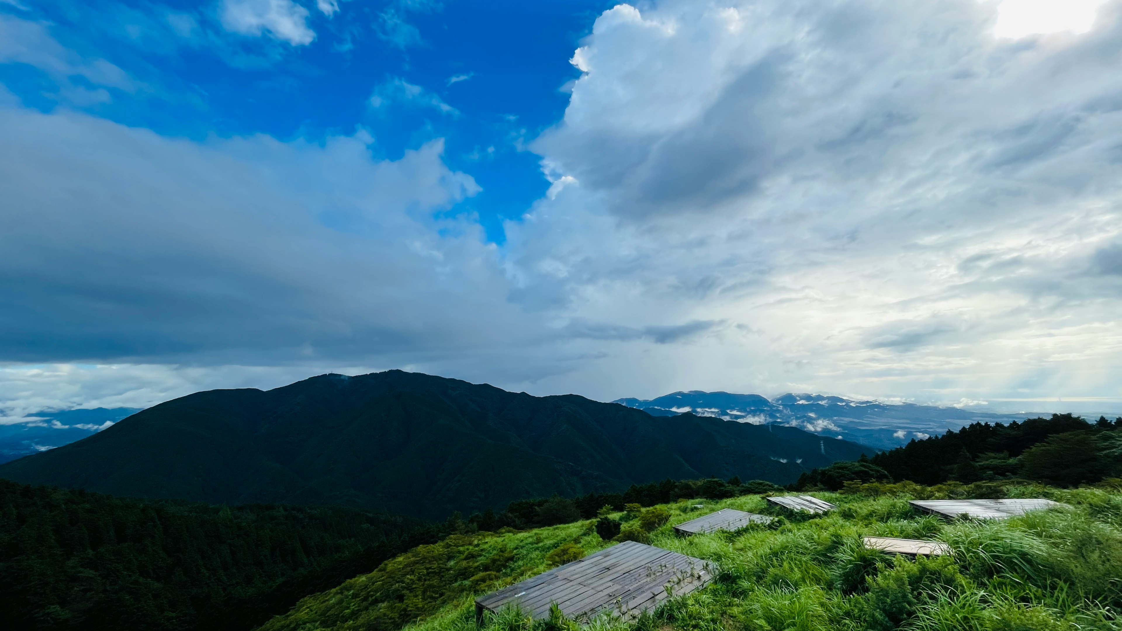 山景藍天和雲朵綠色草地和岩石可見