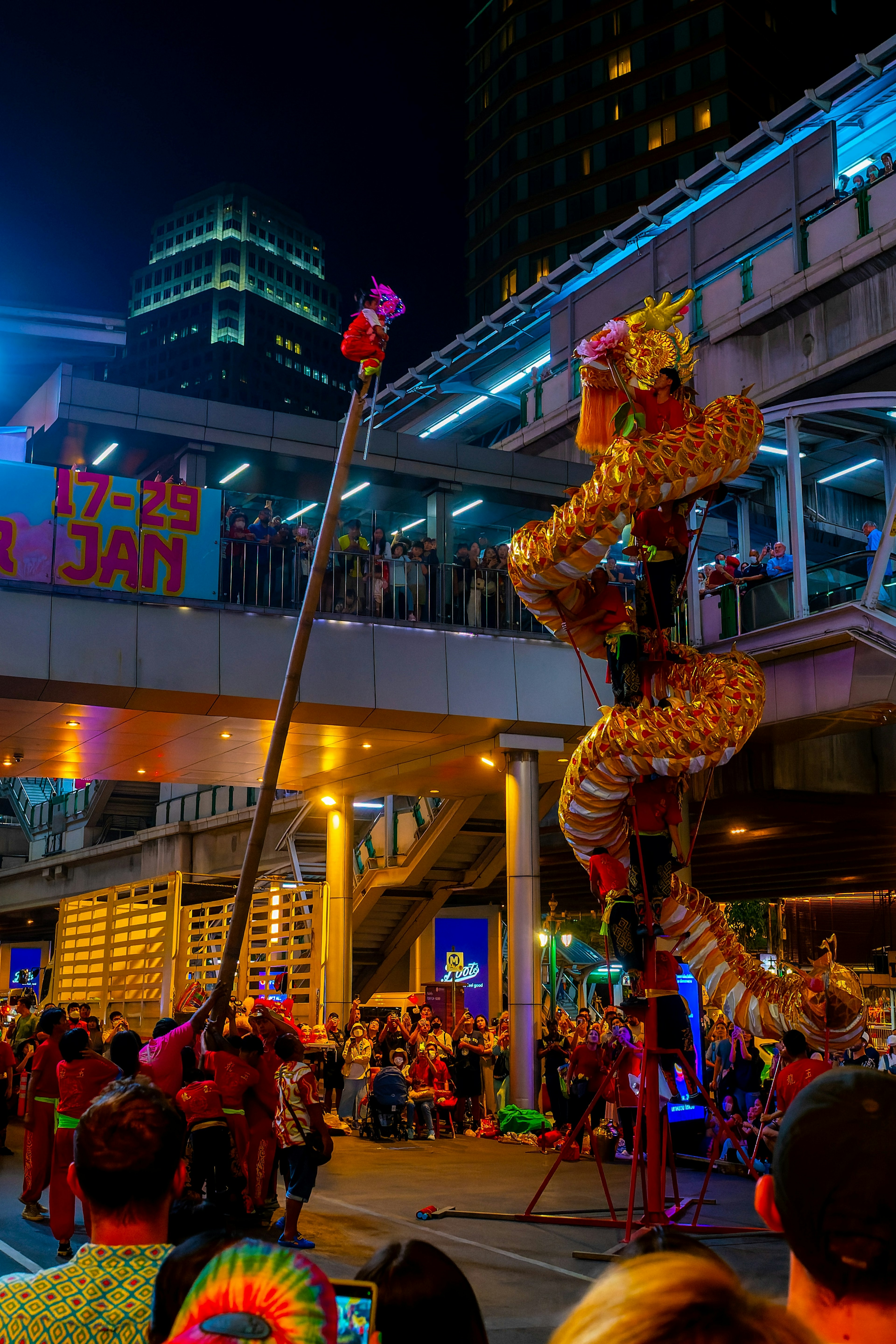 Parade warna-warni di malam hari dengan naga emas yang tampil di tengah kerumunan yang ramai