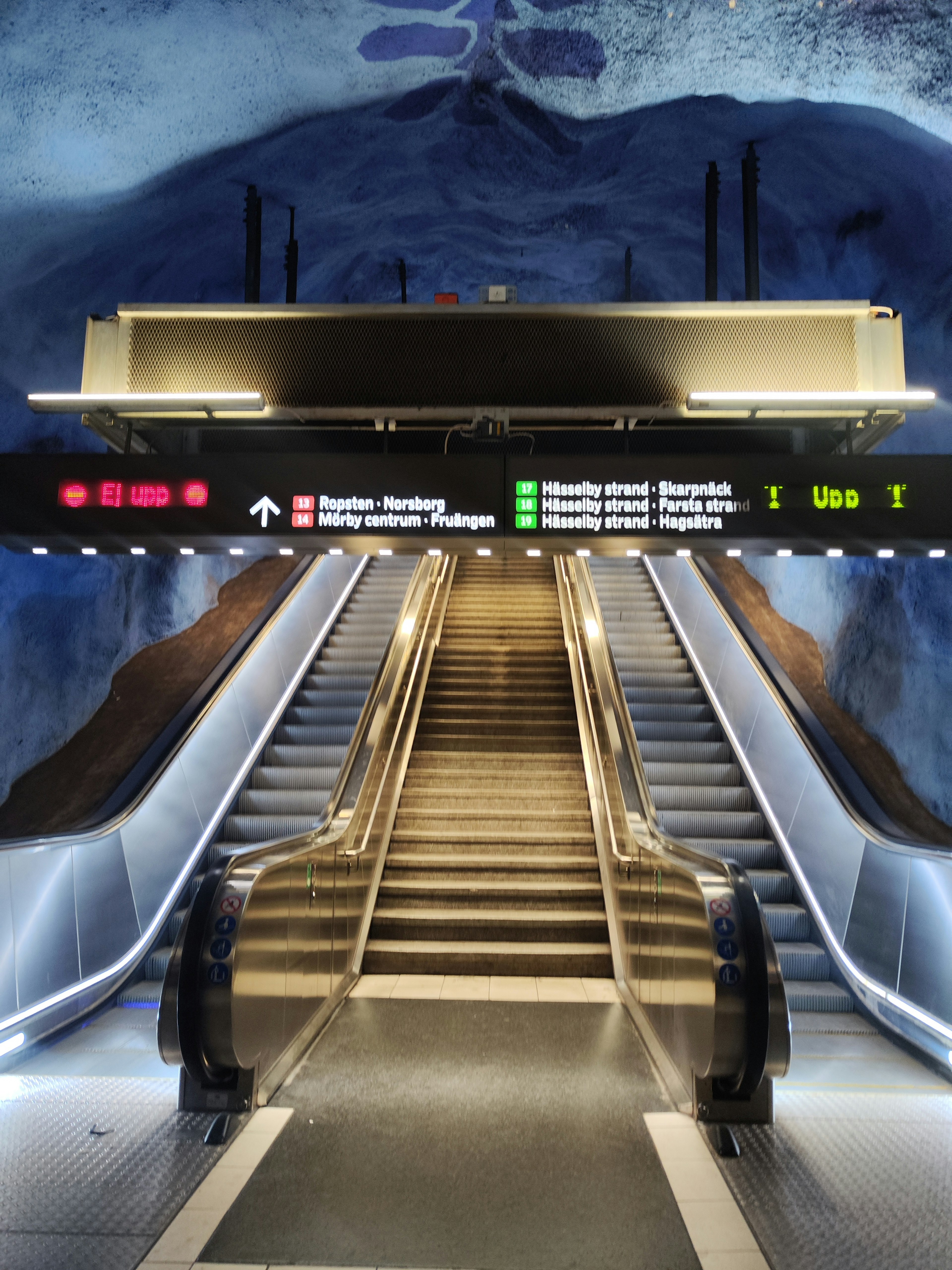 Escalator in a subway station with blue mural