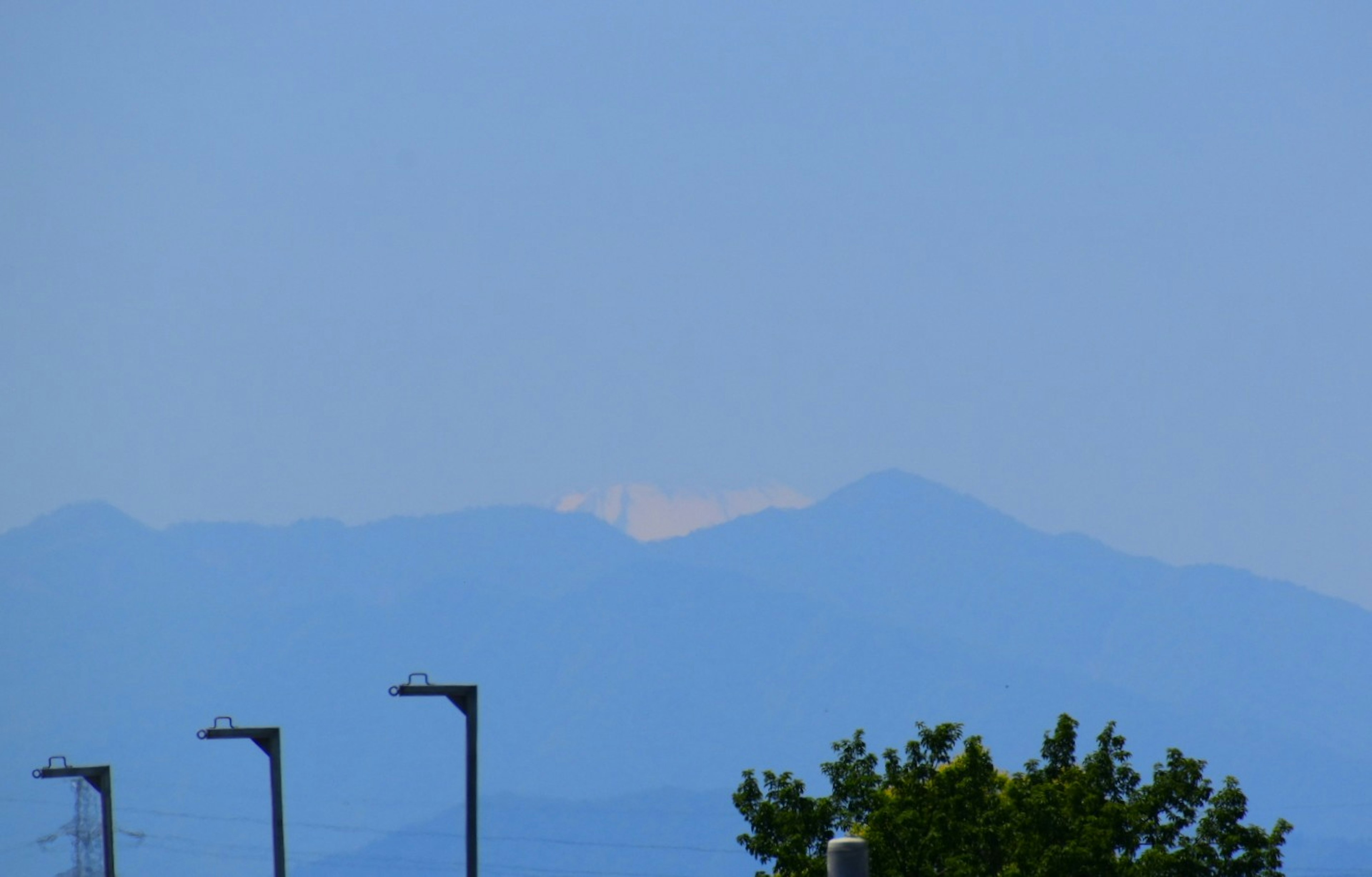 青い空と山々の景色に街灯が並ぶ風景