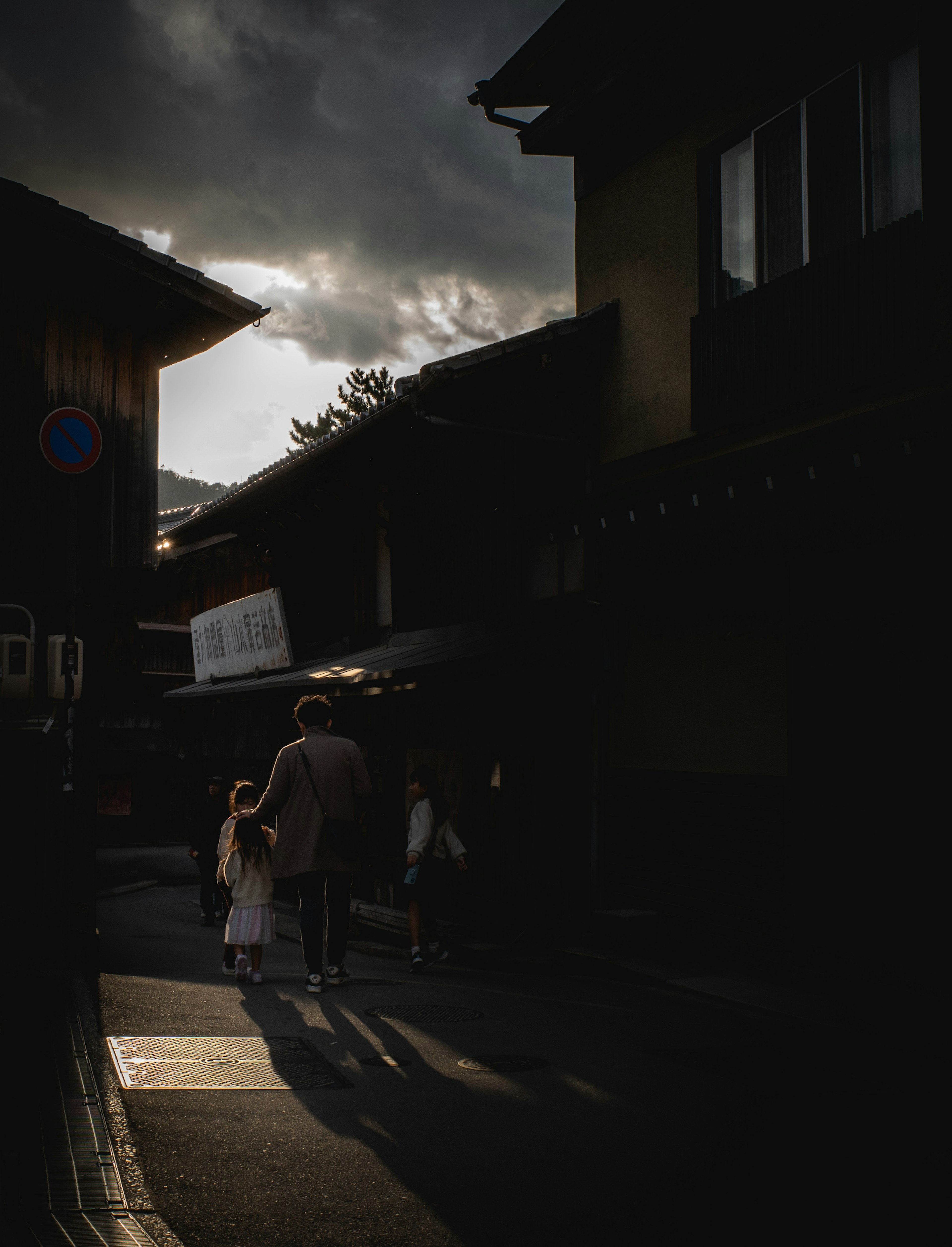 Silhouette d'un parent et d'un enfant marchant dans une rue sombre avec des ombres