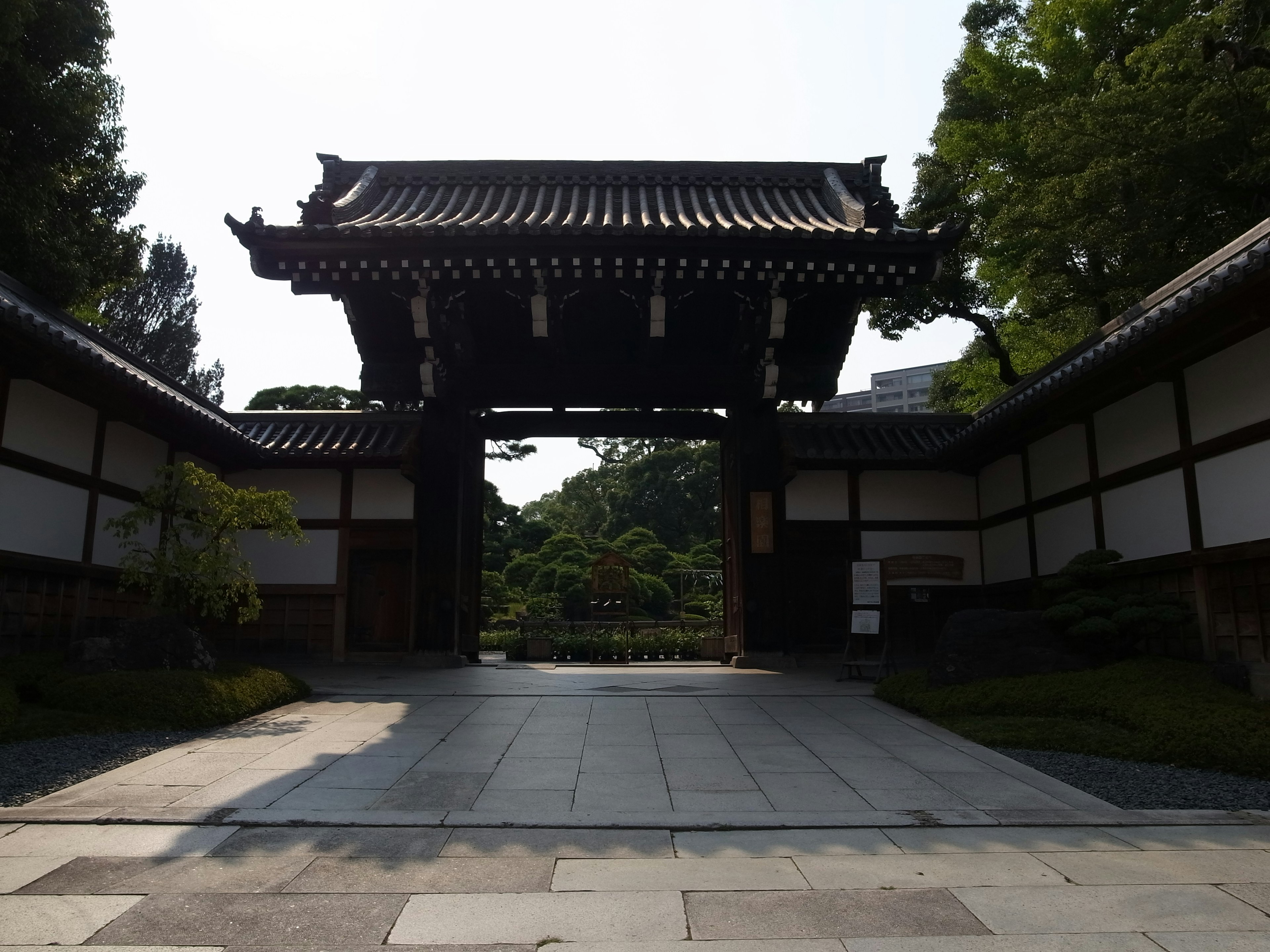 Traditional Japanese gate surrounded by lush greenery and a serene garden