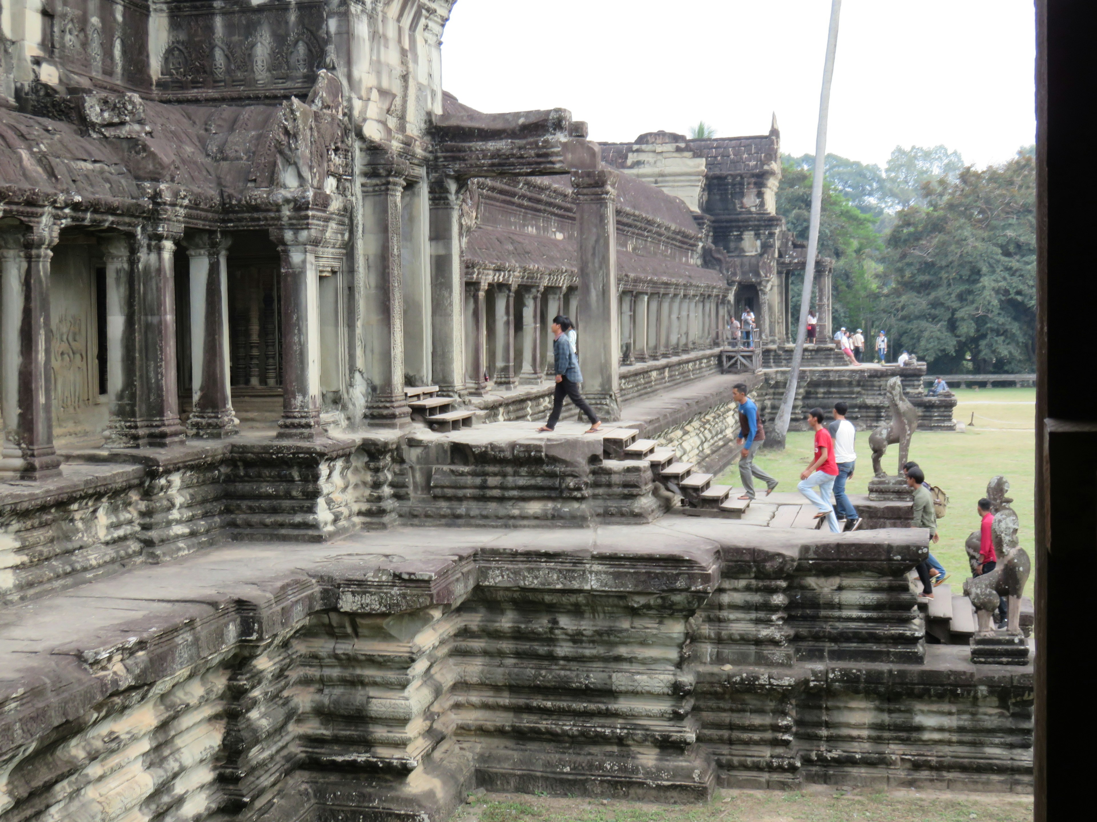 アンコールワットの古代の石造りの階段と遺跡を歩く観光客