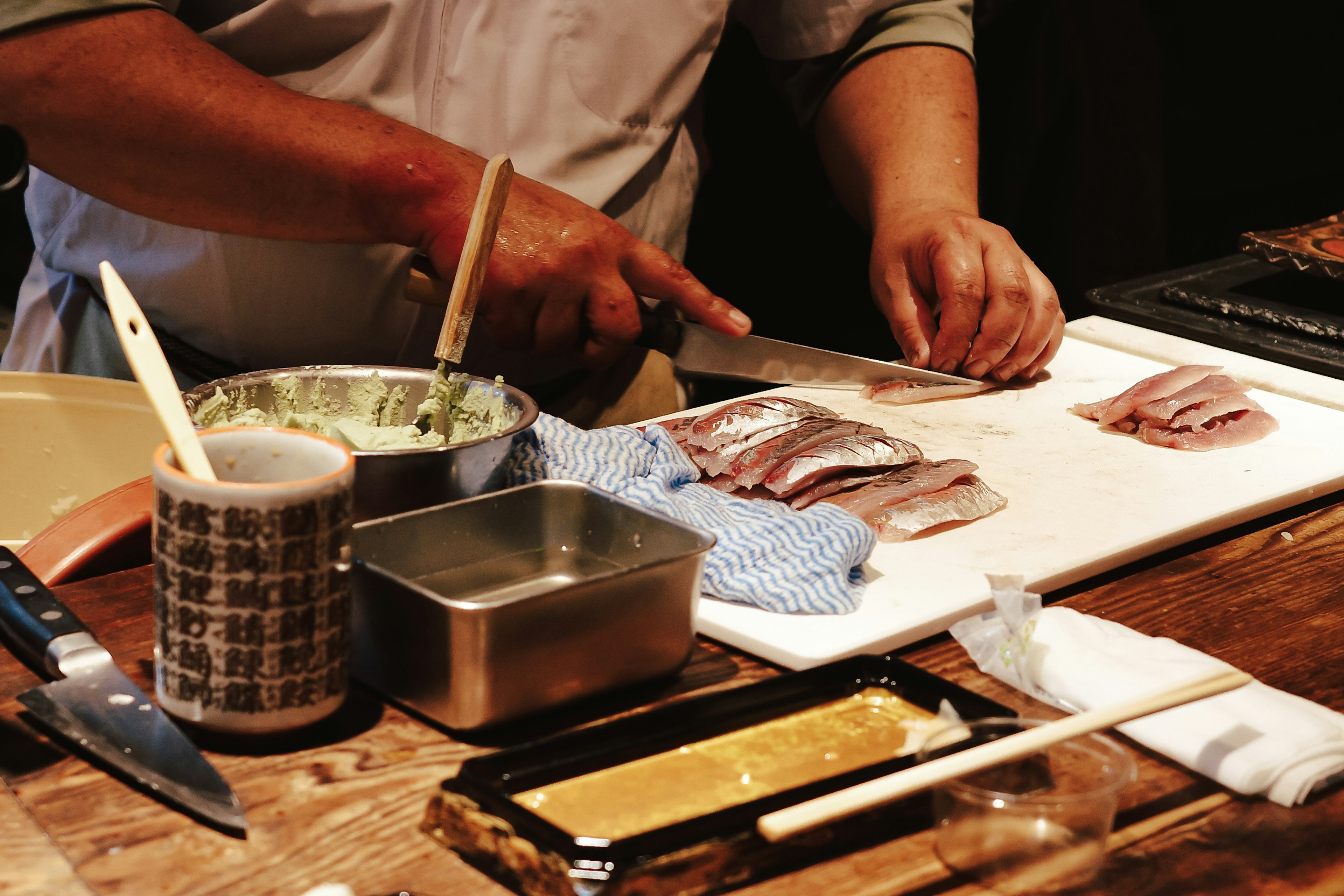 Chef preparando pescado con técnica de corte y utensilios circundantes